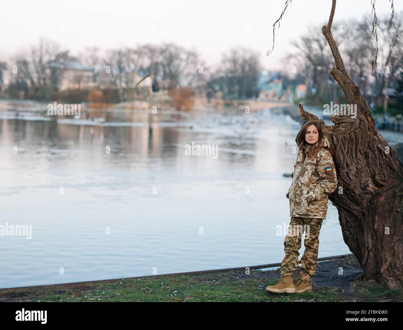 Soldato ucraino che riposa nel parco durante le vacanze vicino al lago. Donne e guerra in Ucraina. Invasione militare russa. Traduzione dall'ucraino: AR Foto Stock
