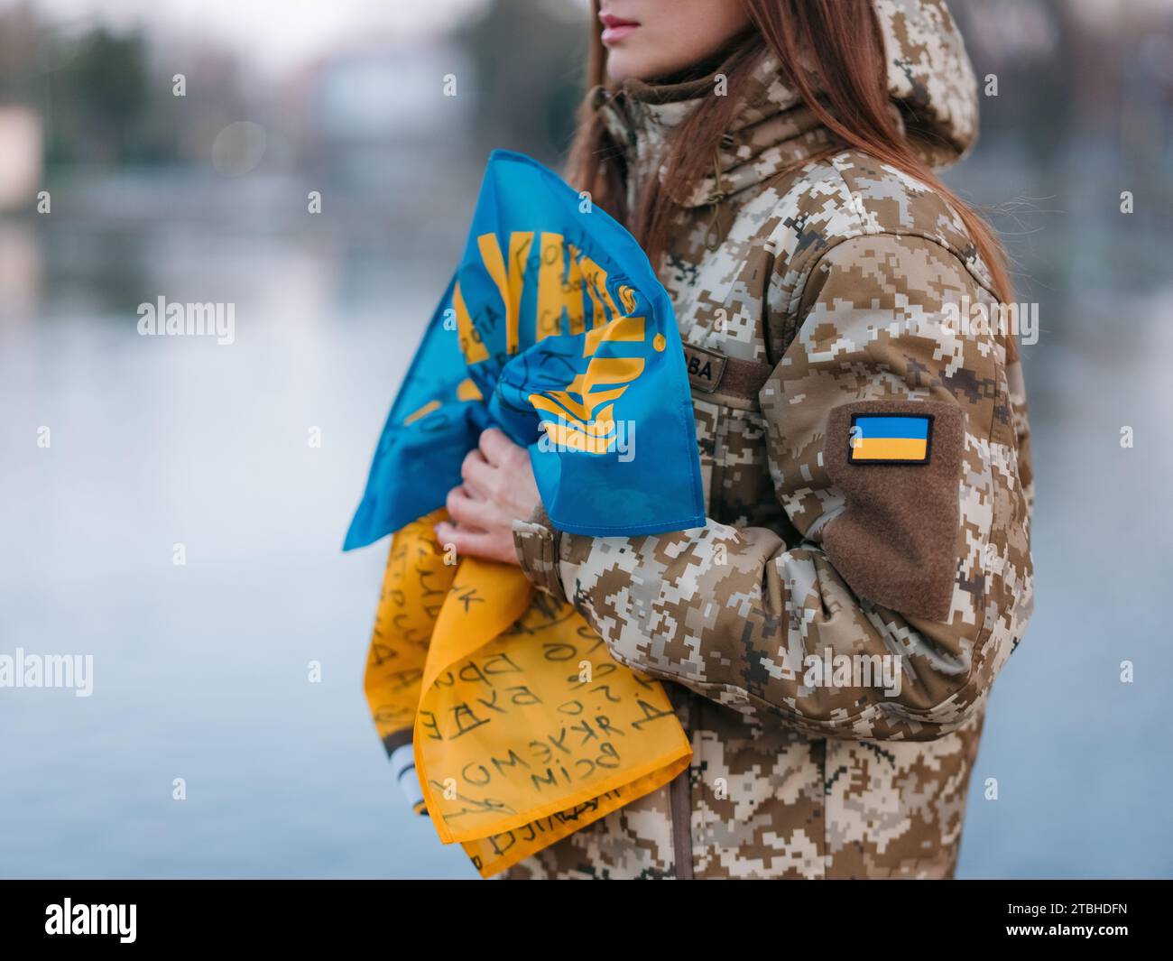 Soldato ucraino che tiene bandiera con le firme dei guerrieri ucraini e riposa nel parco in vacanza. Traduzione dall'ucraino: Gloria a Ukrai Foto Stock