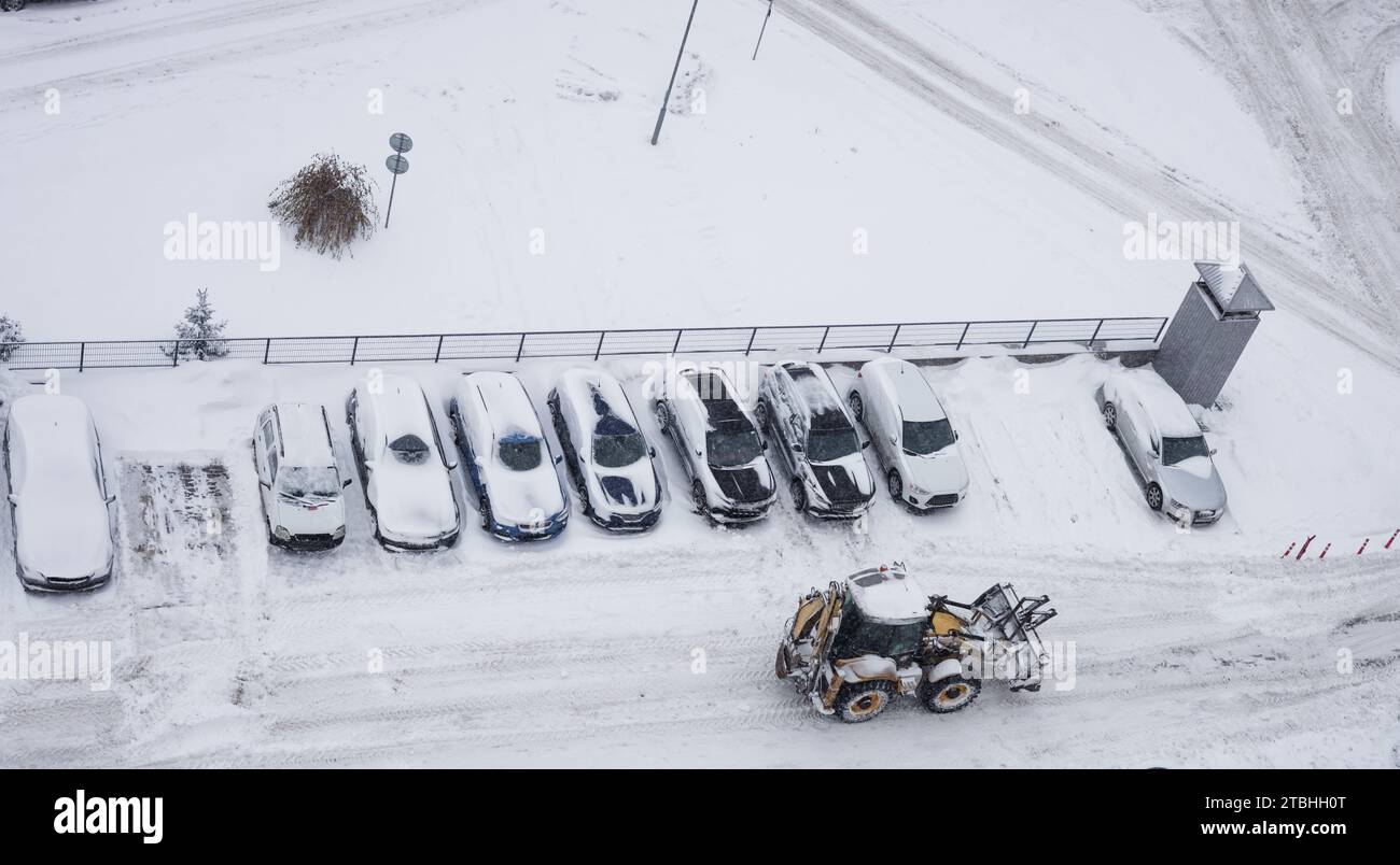 Vista dall'alto su una grande macchina che pulisce le strade cittadine, rimuove neve e ghiaccio. Spazzaneve all'aperto strade pulite su marciapiede Foto Stock