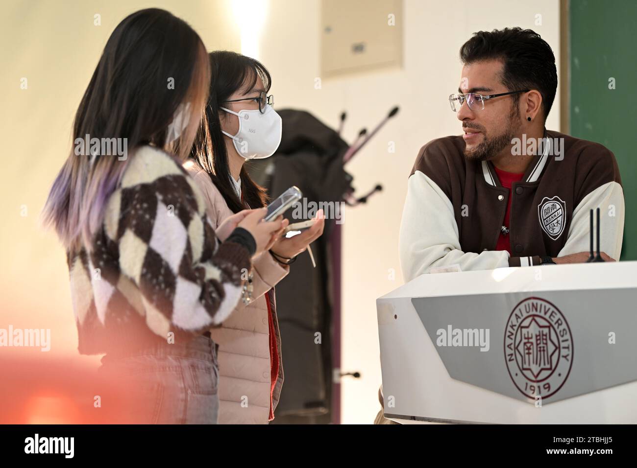 (231207) -- TIANJIN, 7 dicembre 2023 (Xinhua) -- Raydis Franco (1st R) parla con gli studenti durante una pausa di classe all'Università di Nankai, nella provincia di Tianjin nella Cina settentrionale, 4 dicembre 2023. Raydis Franco dal Venezuela e Santiago Arag¨®n dalla Spagna sono entrambi insegnanti di spagnolo che lavorano presso il College of Foreign Languages dell'Università Nankai, nel nord della Cina, a Tianjin. Attratti dalla cultura cinese, hanno iniziato a imparare ed eseguire il cross-talk cinese in spagnolo. Franco è il dougen, un conduttore che fornisce battute e battute, mentre Arag¨®n interpreta il ruolo di penggen, un attore di supporto che reac Foto Stock