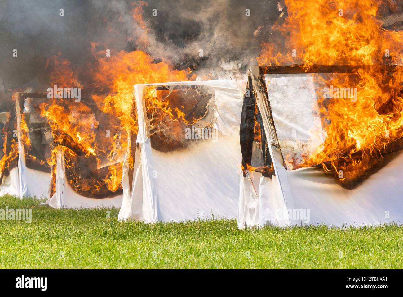 Le tende bianche stanno bruciando in un campo Foto Stock