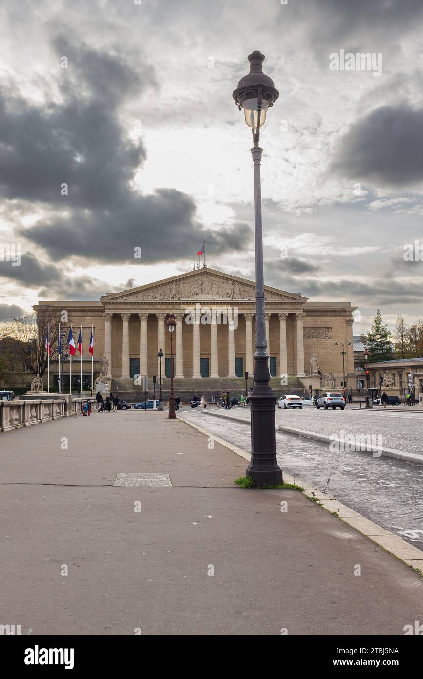 Parigi, Francia, 2023. Persone e automobili che attraversano il Pont de la Concorde verso il Palais Bourbon che ospita l'Assemblea nazionale (verticale) Foto Stock