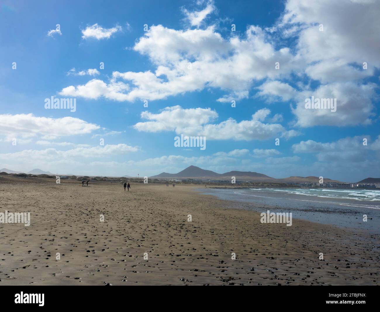 Vista panoramica della spiaggia di Famara. La famosa spiaggia per il surf di Lanzarote. Sullo sfondo le montagne del Risco de Famara. Isole Canarie, Spagna, Europa Foto Stock