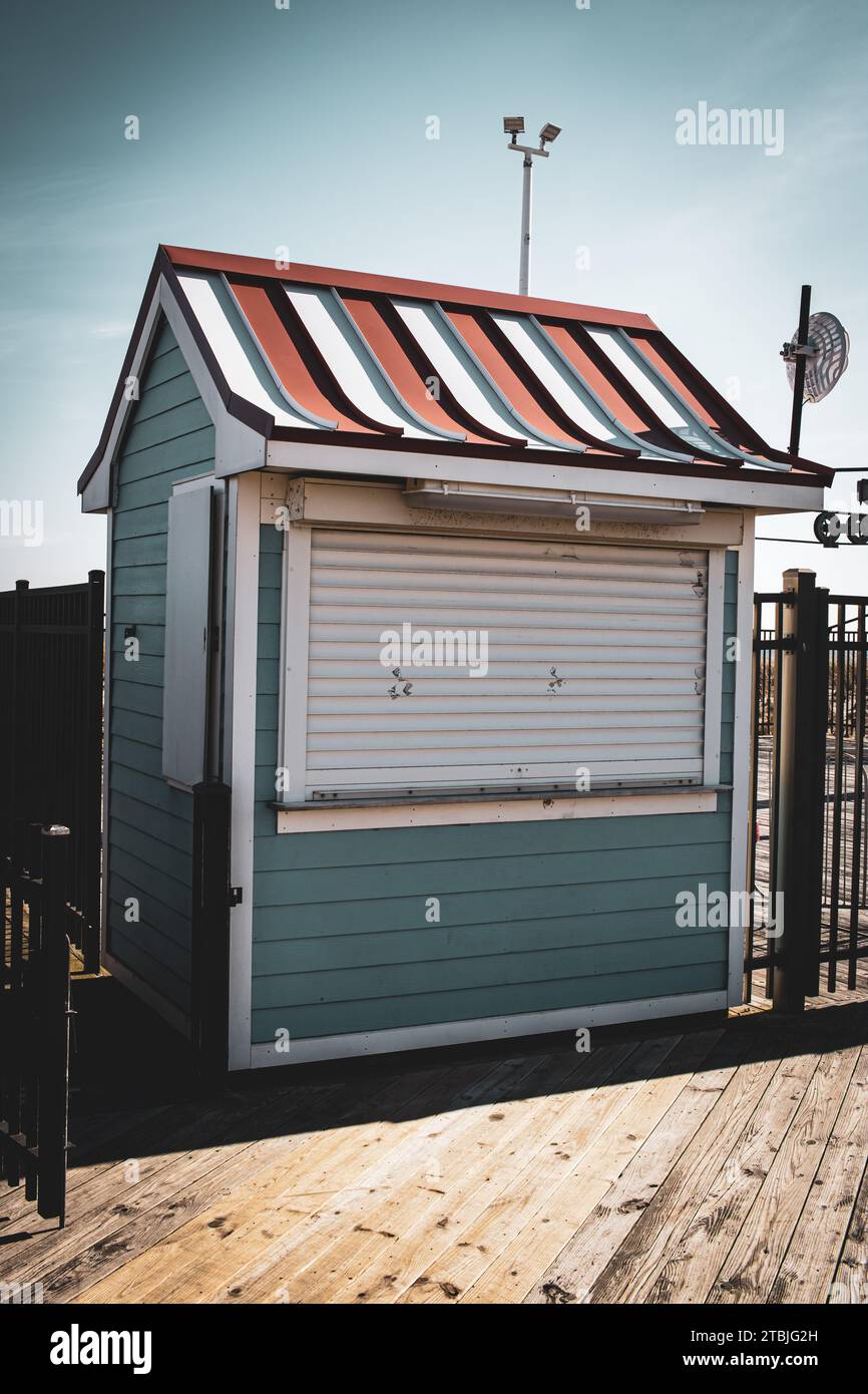 Un piccolo capannone blu arroccato su una piattaforma di legno in una radura circondata da alberi, con un cielo luminoso e soleggiato sullo sfondo Foto Stock