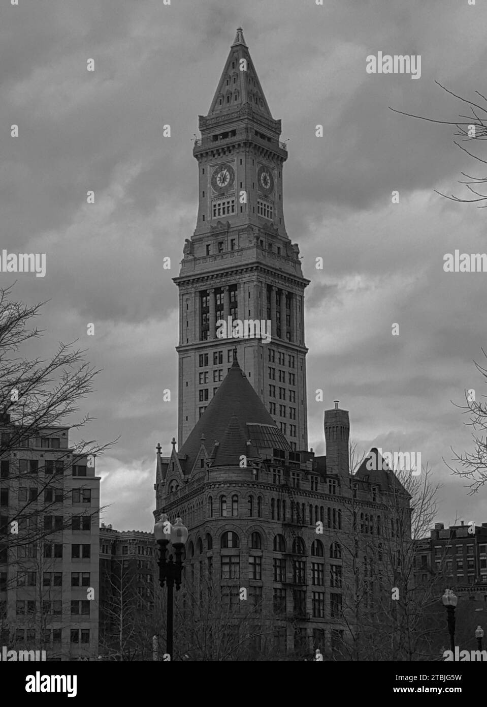 Uno splendido paesaggio urbano caratterizzato da un grande edificio con una torre dell'orologio sullo sfondo, illuminato da una calda luce naturale del mattino Foto Stock