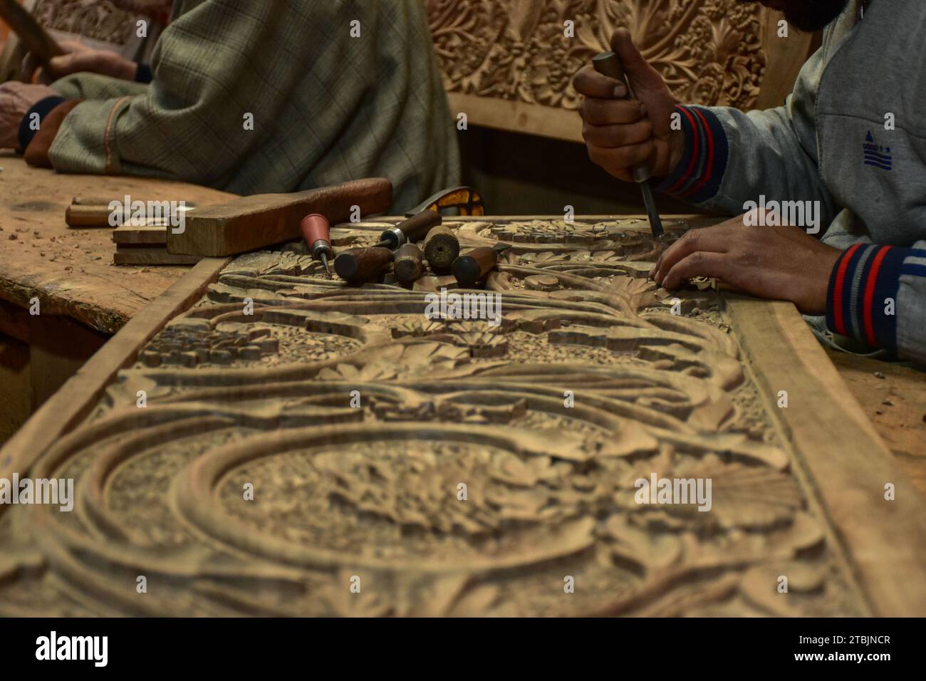 Srinagar, India. 7 dicembre 2023. Un artigiano Kashmiri intaglia un oggetto artigianale in una fabbrica di intaglio del legno. Il Kashmir, il paradiso sulla terra, si riferisce alla bellezza naturale mozzafiato della regione e all'artigianato tradizionale. Insieme a molti altri tipi di arte, il Kashmir è rinomato per la sua tecnica unica di intaglio del legno. L'intaglio in legno Kashmiri è molto richiesto sia all'interno che all'esterno dello stato. Il suo mercato è cresciuto sia a livello locale che globale nel corso degli anni. Ma al giorno d'oggi, gli artigiani stanno lottando per mantenere viva questa arte. La maggior parte dei prodotti realizzati da questi artigiani non ottiene abbastanza profitti, a causa di Foto Stock