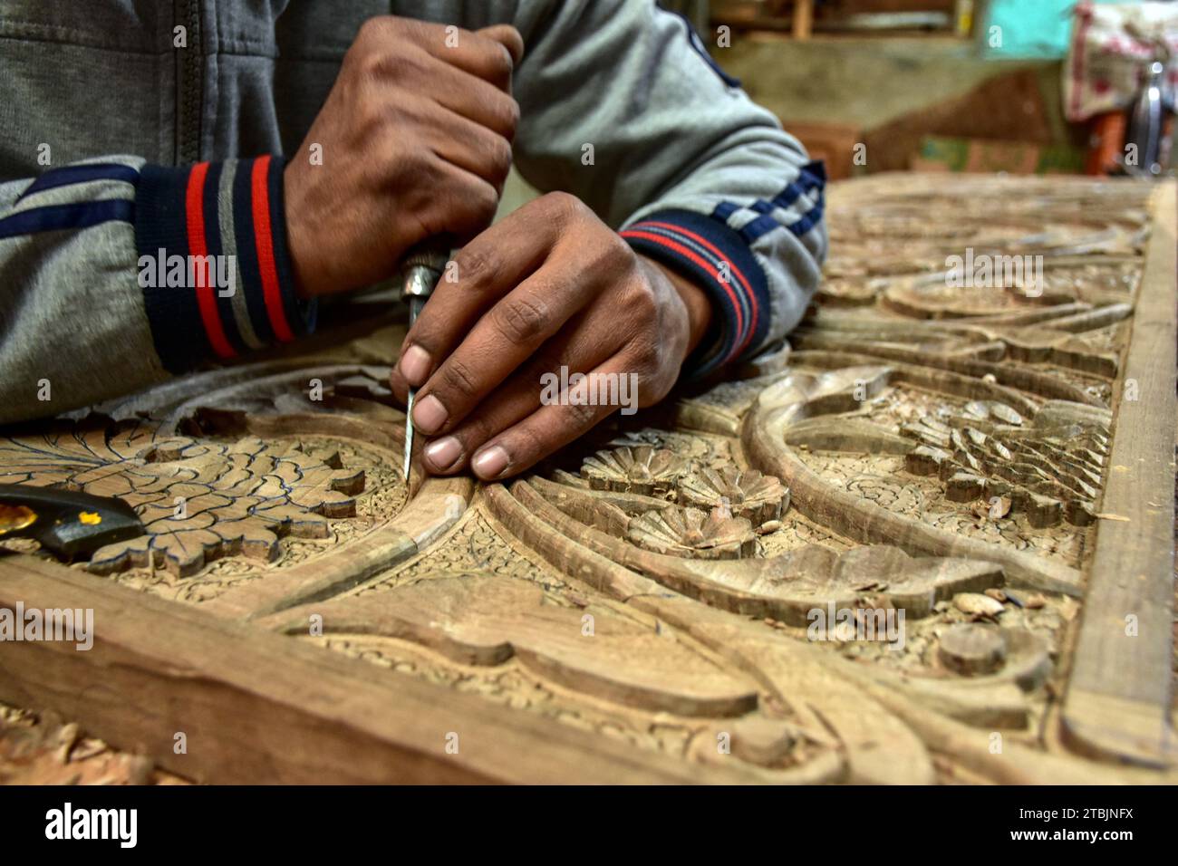 Srinagar, India. 7 dicembre 2023. Un artigiano Kashmiri intaglia un oggetto artigianale in una fabbrica di intaglio del legno. Il Kashmir, il paradiso sulla terra, si riferisce alla bellezza naturale mozzafiato della regione e all'artigianato tradizionale. Insieme a molti altri tipi di arte, il Kashmir è rinomato per la sua tecnica unica di intaglio del legno. L'intaglio in legno Kashmiri è molto richiesto sia all'interno che all'esterno dello stato. Il suo mercato è cresciuto sia a livello locale che globale nel corso degli anni. Ma al giorno d'oggi, gli artigiani stanno lottando per mantenere viva questa arte. La maggior parte dei prodotti realizzati da questi artigiani non ottiene abbastanza profitti, a causa di Foto Stock