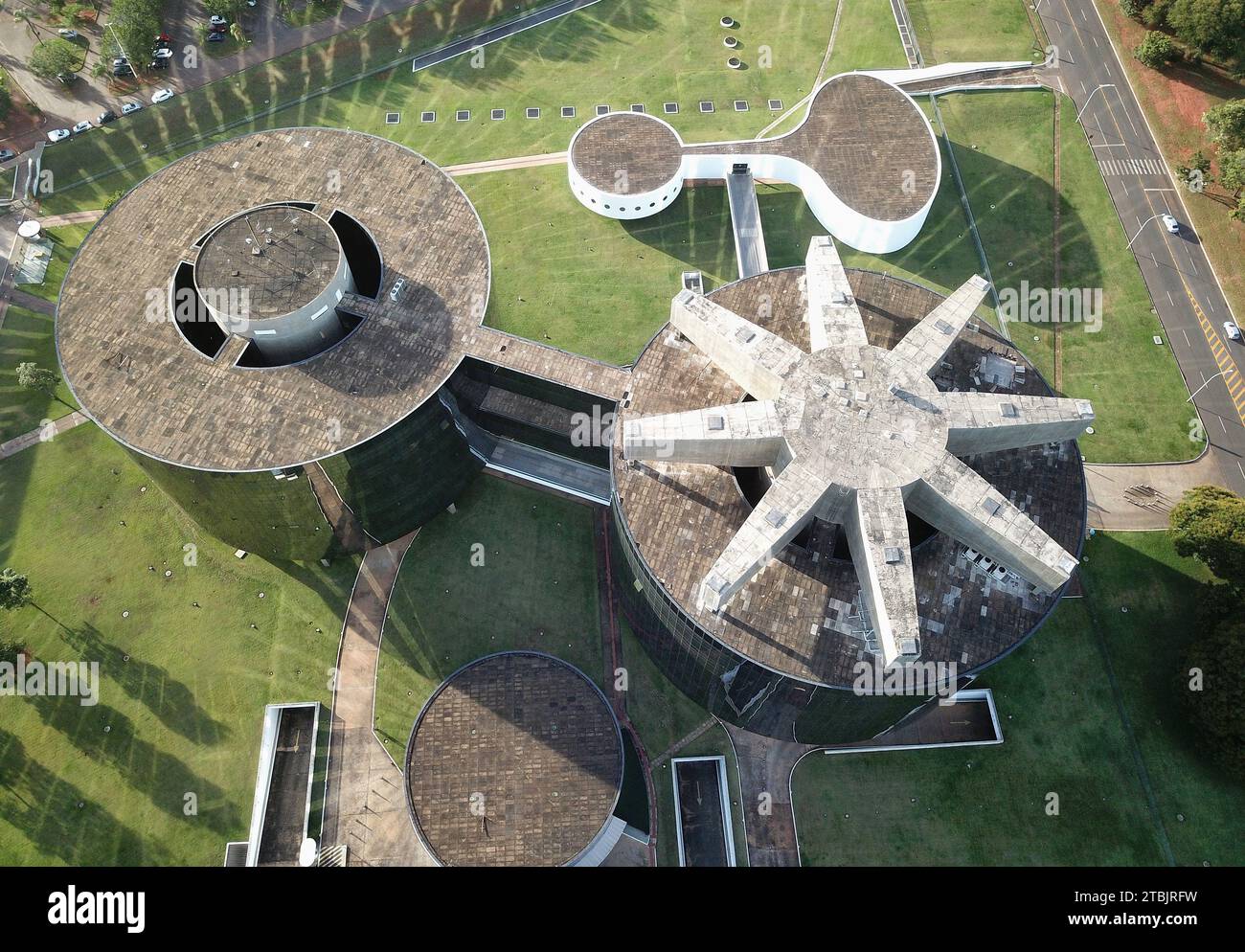 Un primo piano di un moderno tetto in metallo con dettagli circolari, circondato da lussureggianti alberi verdi ed erba Foto Stock