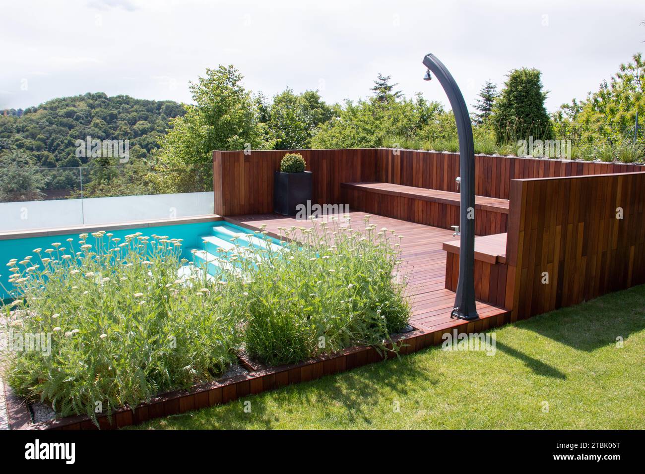 Terrazza a bordo piscina nel verde giardino con vista del paesaggio naturale sullo sfondo Foto Stock