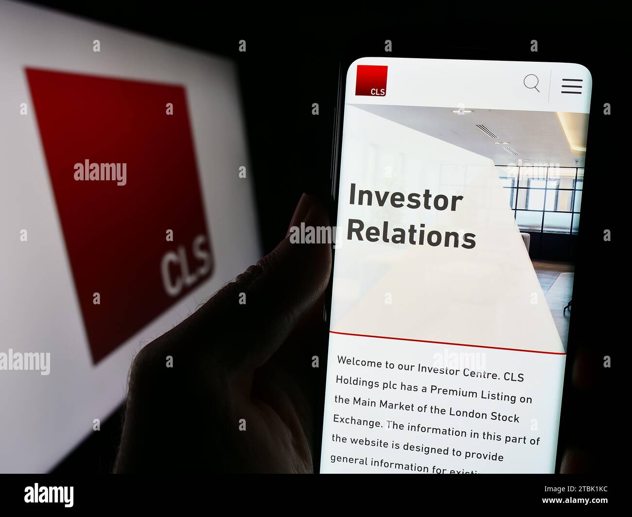 Persona che possiede un telefono cellulare con il sito Web della società britannica di investimento immobiliare CLS Holdings plc con logo. Concentrarsi sul centro del display del telefono. Foto Stock