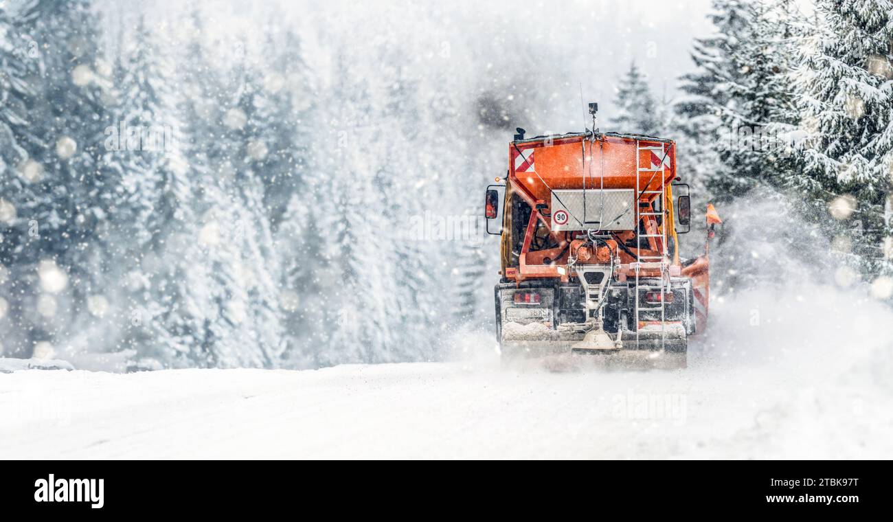 Spazzaneve su strada salata autostradale . Sbrinamento camion arancione. Manutenzione gritter invernale panorama o banner largo veicolo. Foto Stock