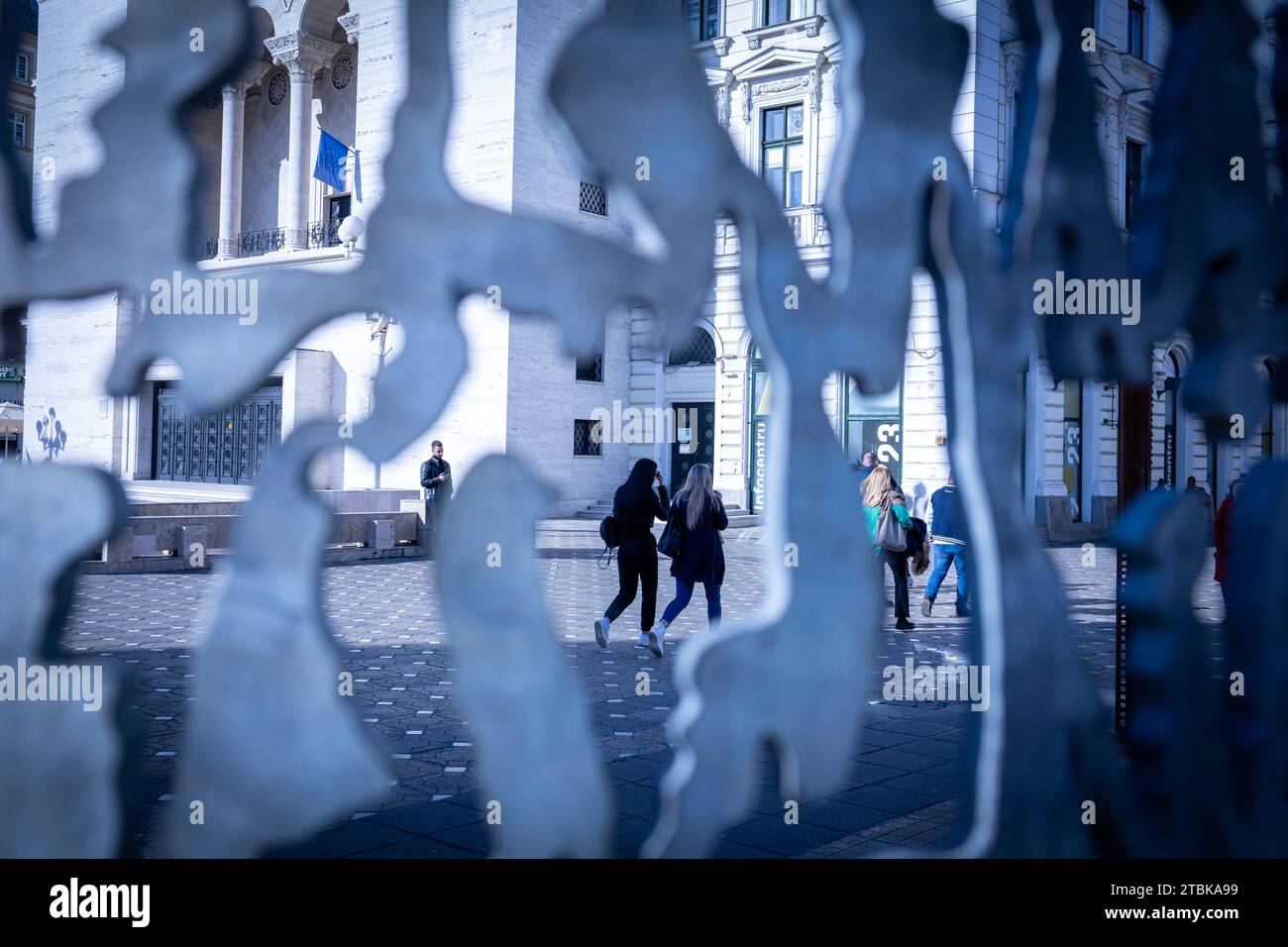 Un variegato gruppo di individui cammina lungo un trafficato marciapiede della città, circondato da alti edifici e architettura moderni Foto Stock