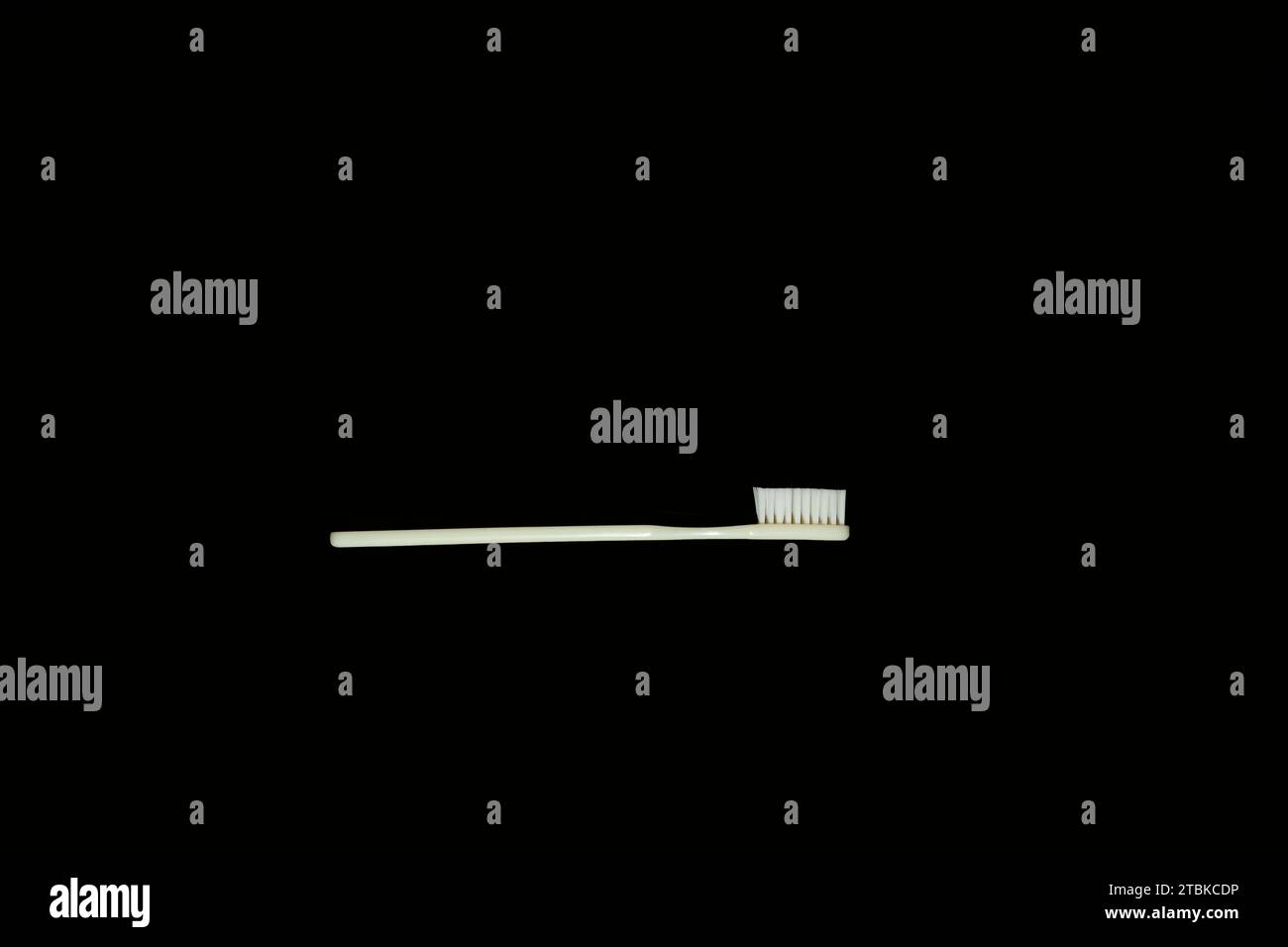 Uno spazzolino bianco invecchiato poggia su uno sfondo nero, mostrando un aspetto pulito e rinnovato Foto Stock