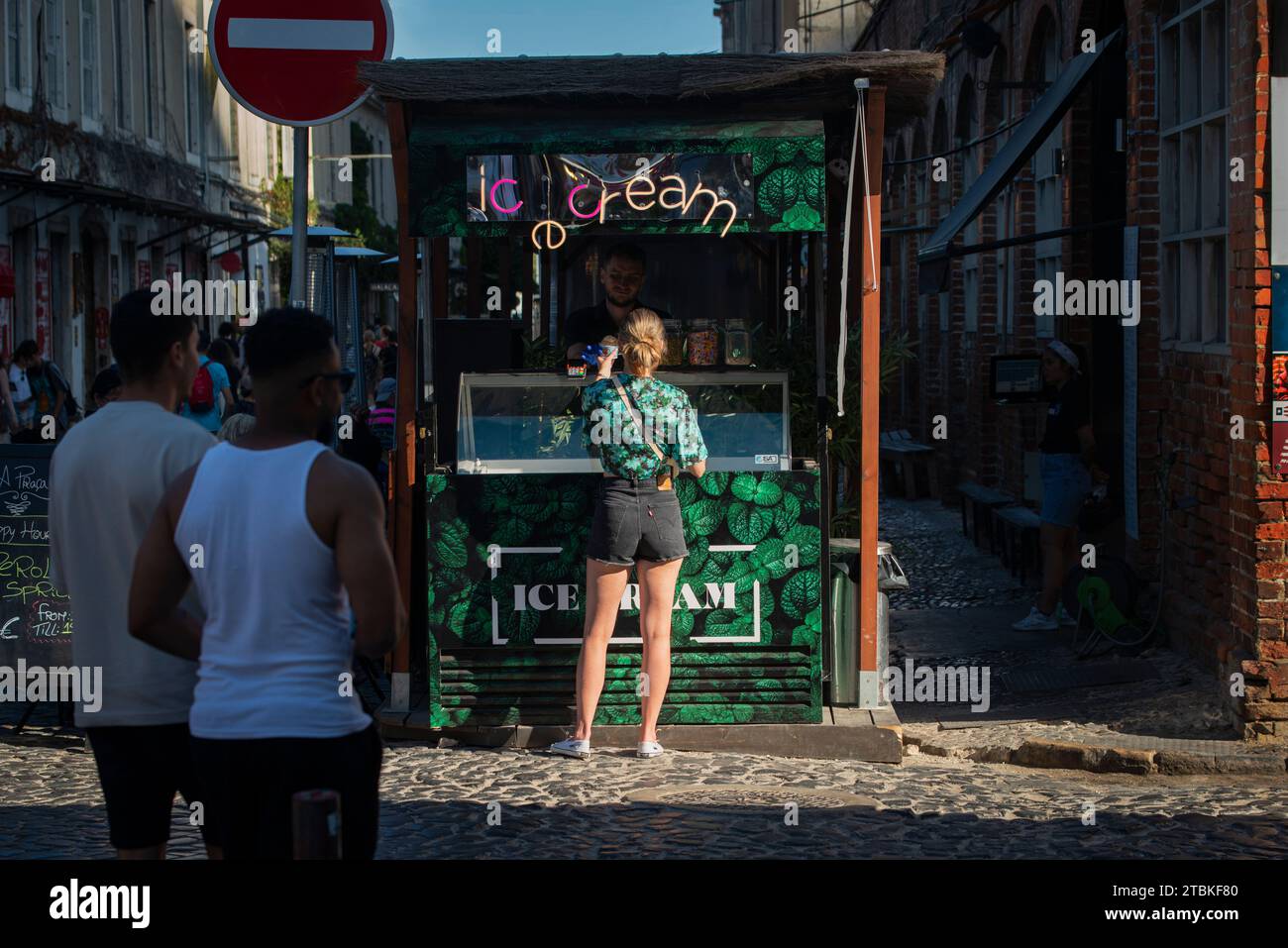 LX Factory, Lisbona, Portogallo. Giovane donna che acquista un gelato in un chiosco all'ingresso nord della fabbrica. La LX Factory è un parco industriale ristrutturato di 23.000 metri quadrati che è diventato un centro di arte, multimedia, negozi di musica, cibo e intrattenimento a 3 km (1,8 miglia) ad ovest del centro di Lisbona. Foto Stock