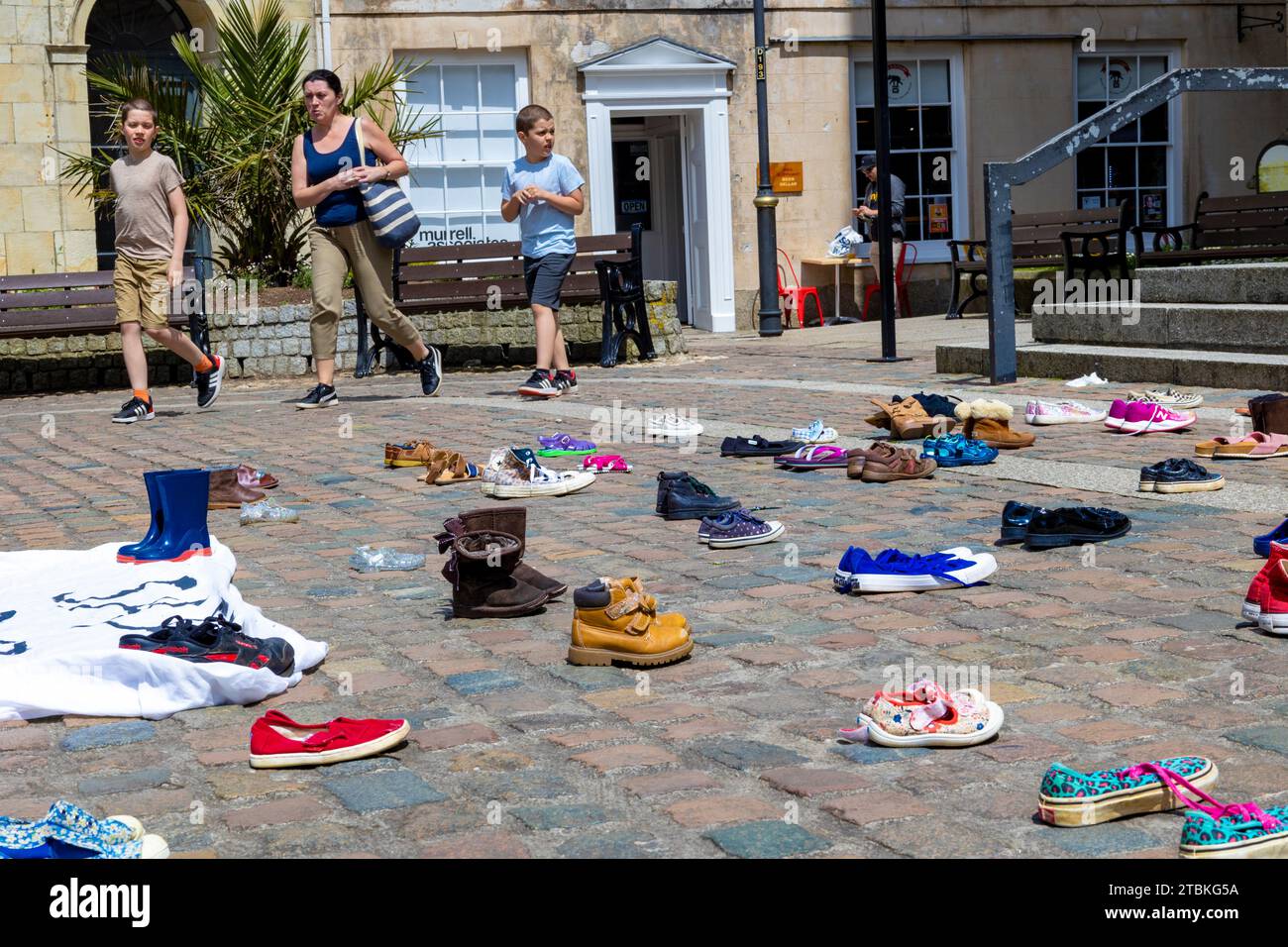 “Abbiamo abbandonato queste scarpe fuori dalla Cattedrale di Truro come i nostri parlamentari hanno abbandonato bambini rifugiati” - le scarpe rappresentano la separazione familiare dei rifugiati. Foto Stock