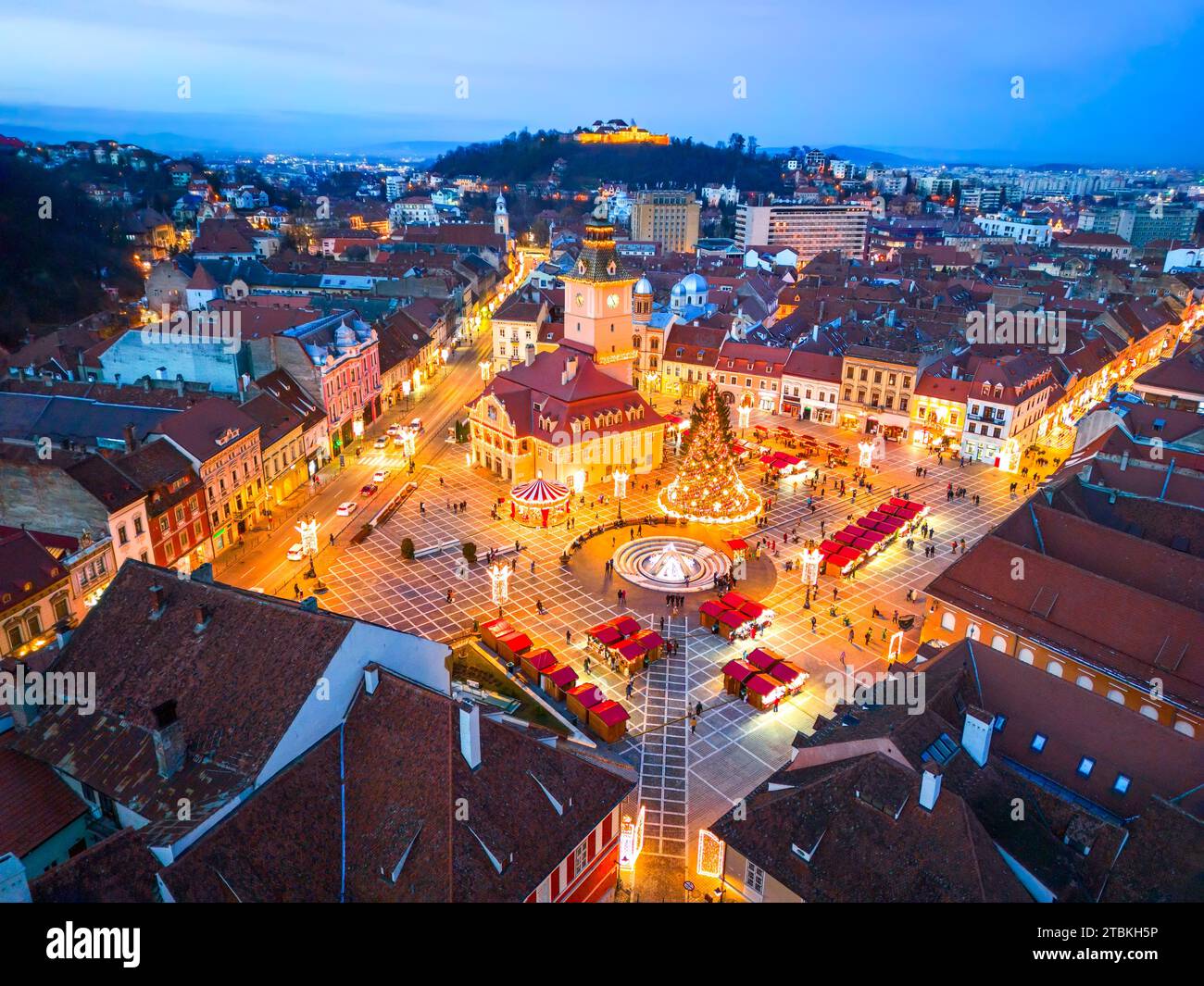 Brasov, Romania. Vista aerea con droni e mercatino di Natale nella piazza principale al crepuscolo, splendida destinazione turistica della Transilvania. Foto Stock