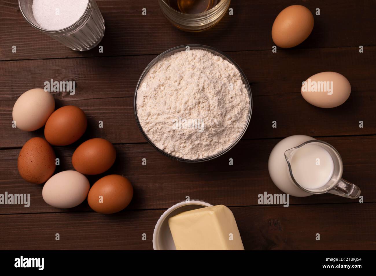 Vista dall'alto degli ingredienti farina di grano, uova, latte, burro, zucchero, cognac su tavolo di legno per Sakotis o Raguolis, torta tradizionale natalizia. Foto Stock