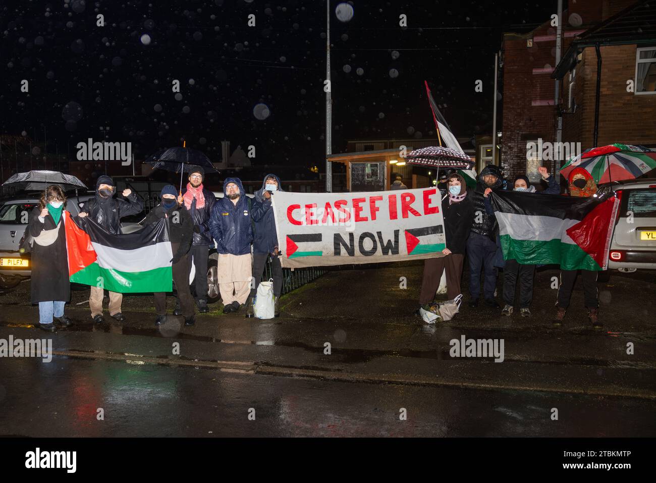 Mirfield, Regno Unito. 07 DEC, 2023. I manifestanti stanno sotto la pioggia battente sulla strada fuori dall'Old Bank Working Man Club (89 Old Bank Rd, Mirfield WF14 0HY) in segno di protesta contro l'evento di raccolta fondi del partito laburista che si svolge lì. L'evento ha visto la partecipazione di Kim Leadbeater, deputato laburista per Batley and Spen e Angela Rayner, vice primo ministro ombra del Regno Unito. Circa 15 attivisti hanno cantato per 2 ore con una significativa presenza della polizia, mentre 2 manifestanti sono entrati brevemente nei locali senza arresti. Credit Milo Chandler/Alamy Live News Foto Stock