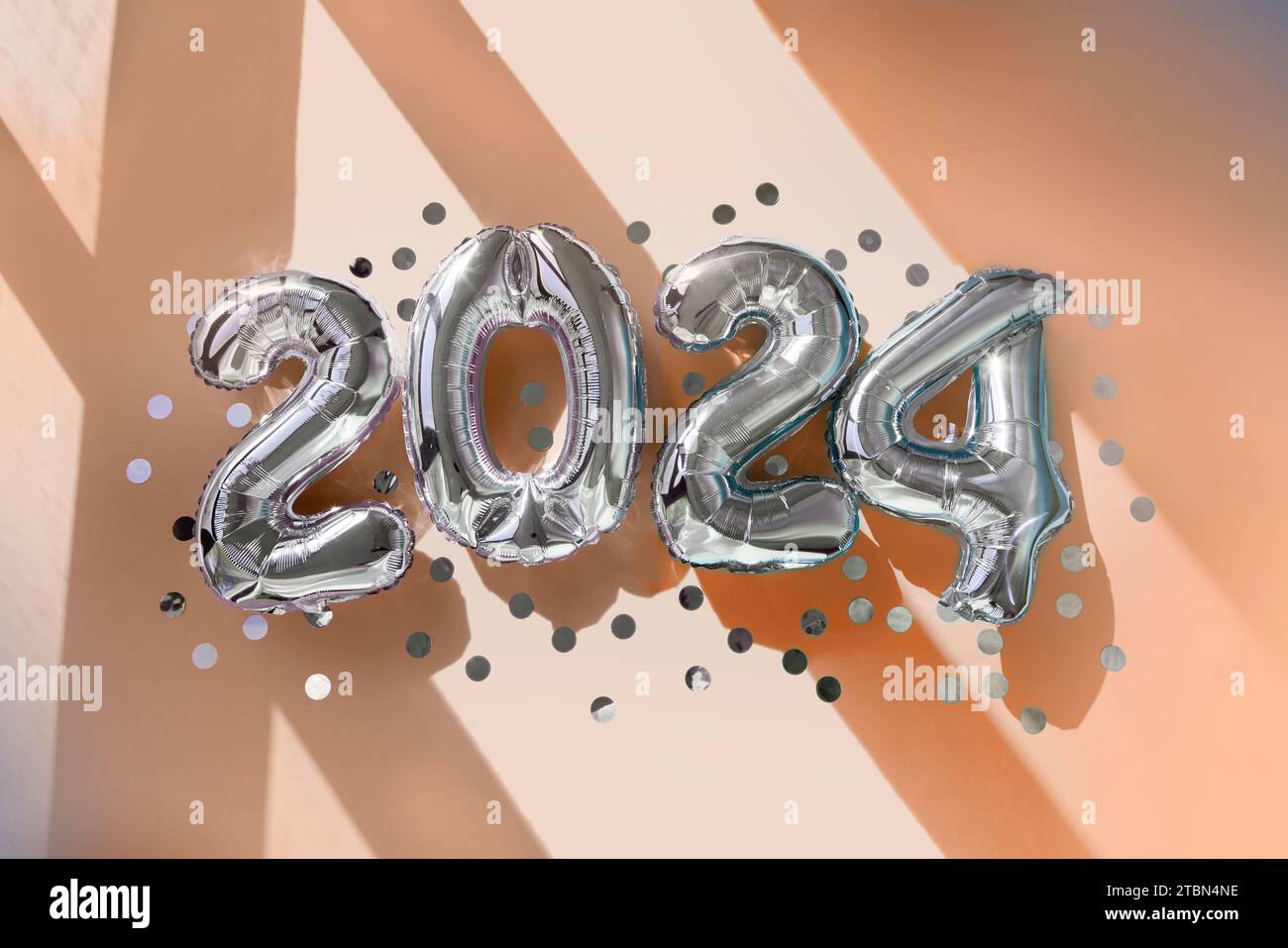 Silver conta 2024 palloncini per il nuovo anno alla luce del sole sullo sfondo di Peach Fuzz Foto Stock