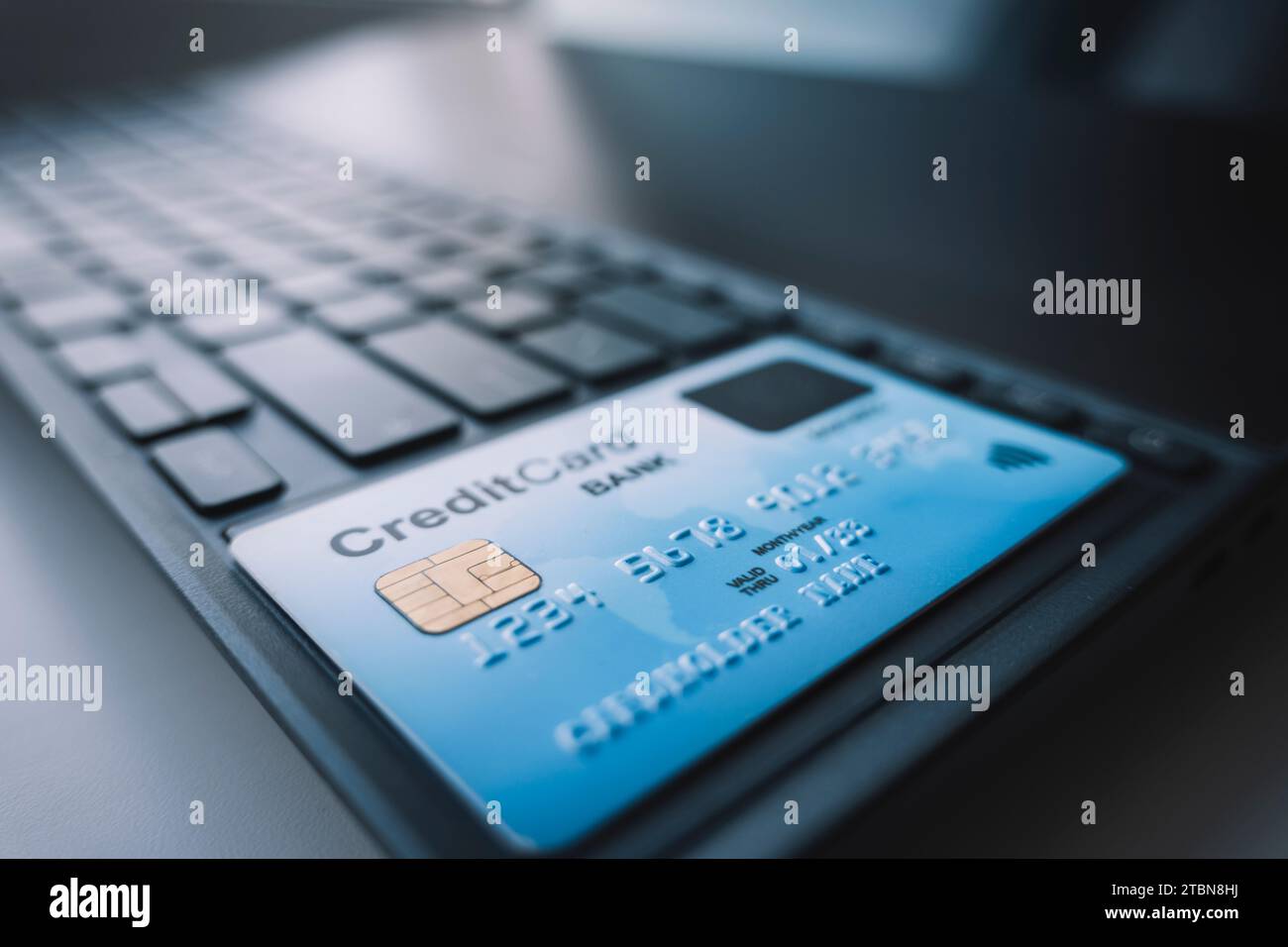 Pagamento tramite carta di credito via Internet. Una scheda di plastica blu è appoggiata su una tastiera nera del computer portatile. lettura pagamento con carta nfc Foto Stock