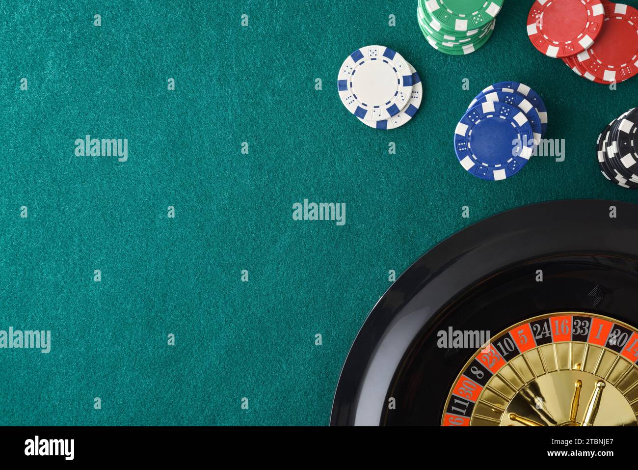 Roulette del casinò su un tappeto di feltro verde e gettoni in un angolo. Vista dall'alto. Foto Stock