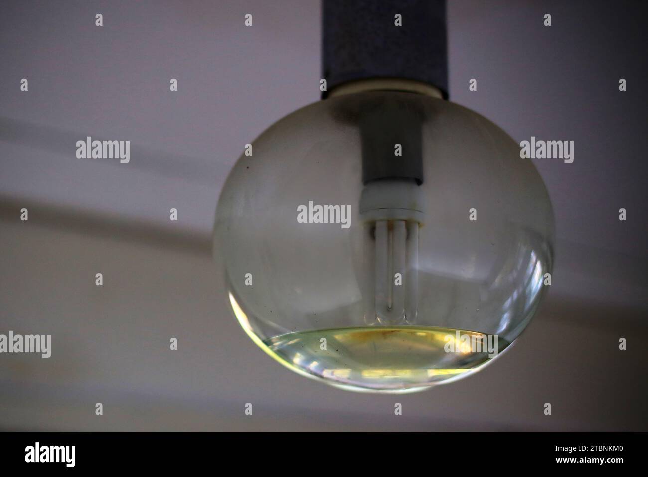 Vaschetta di vetro di una lampada da soffitto parzialmente riempita a causa di danni causati dall'acqua. Foto Stock