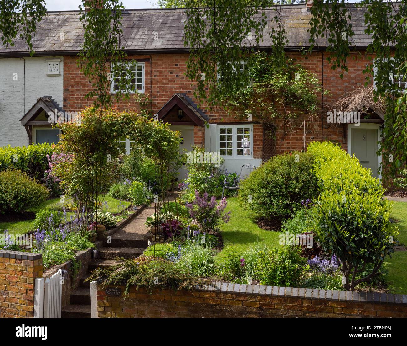 Fila di cottage terrazzati con giardini ben forniti, Abthorpe Village, Northamptonshire, Regno Unito Foto Stock