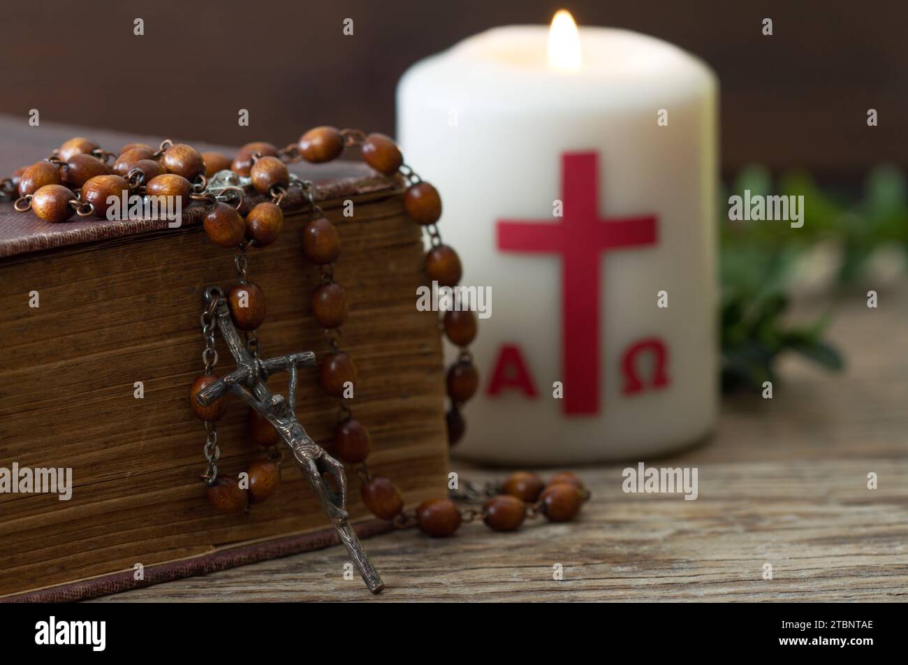 Croce di legno con bibbia, rosario e candela pasquale, concetto religioso pasquale Foto Stock