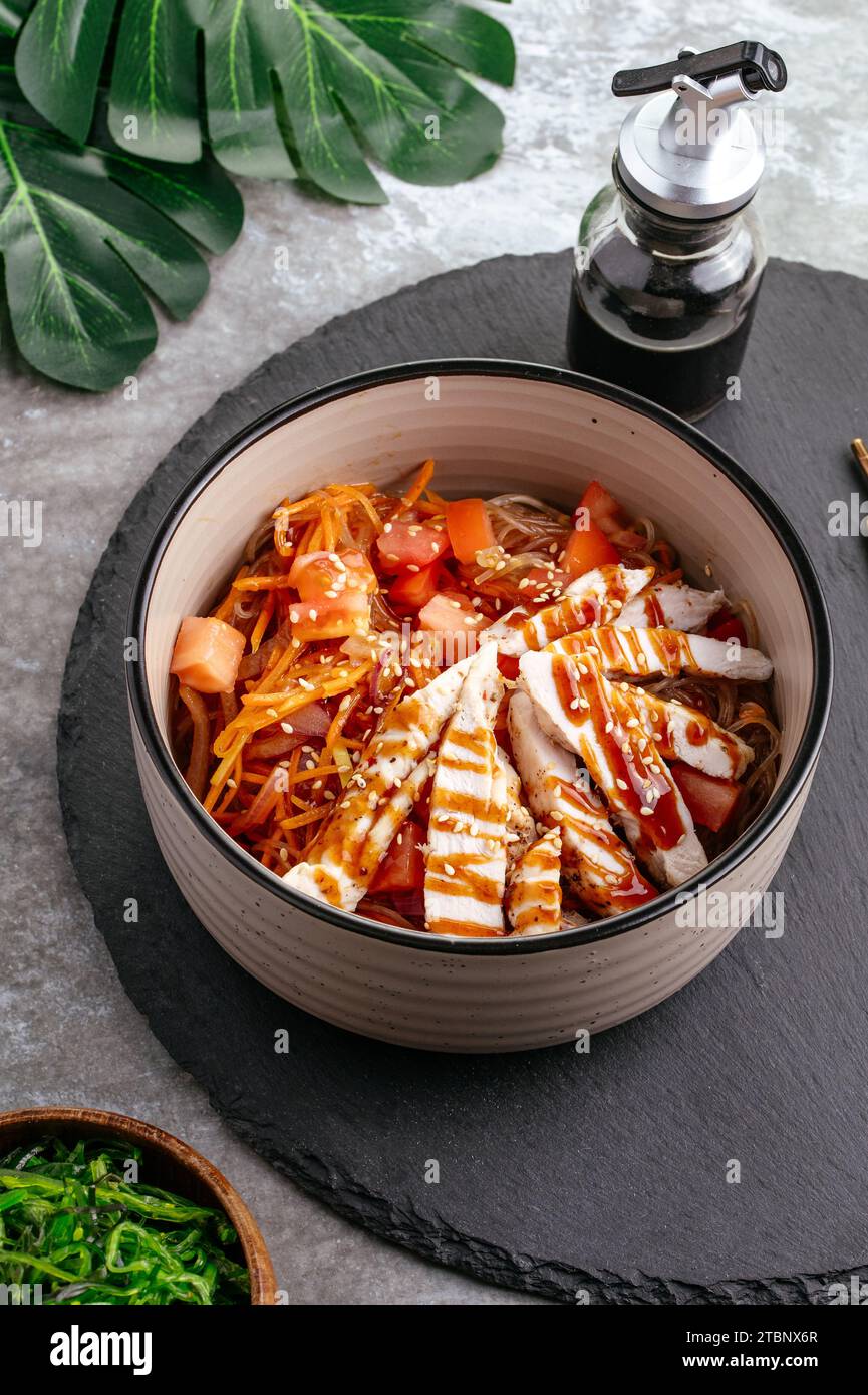Spaghetti di riso asiatici con verdure, salsa e pollo in una ciotola Foto Stock