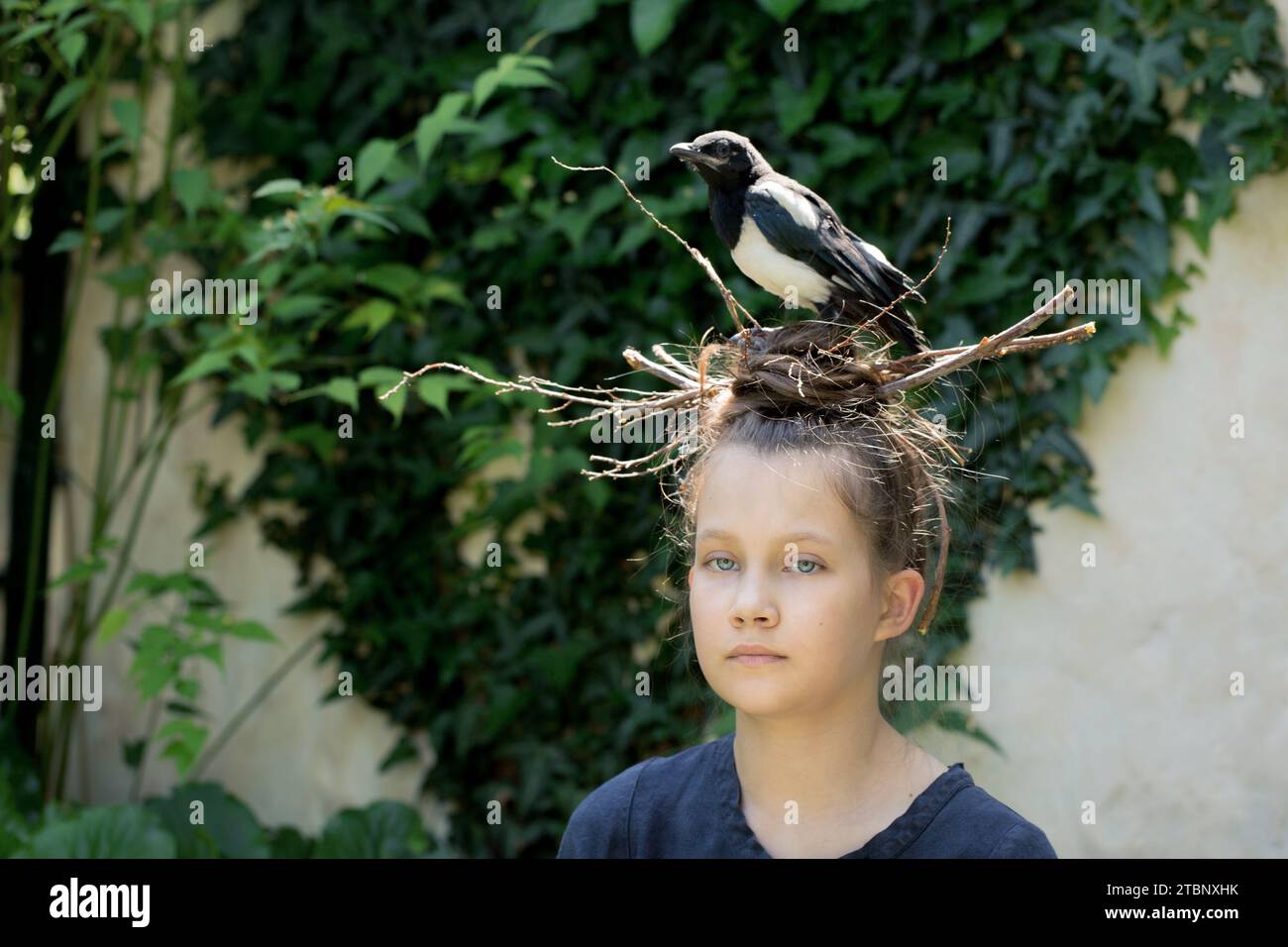 Una ragazza con un nido sulla testa e la sua piccola magpie Foto Stock