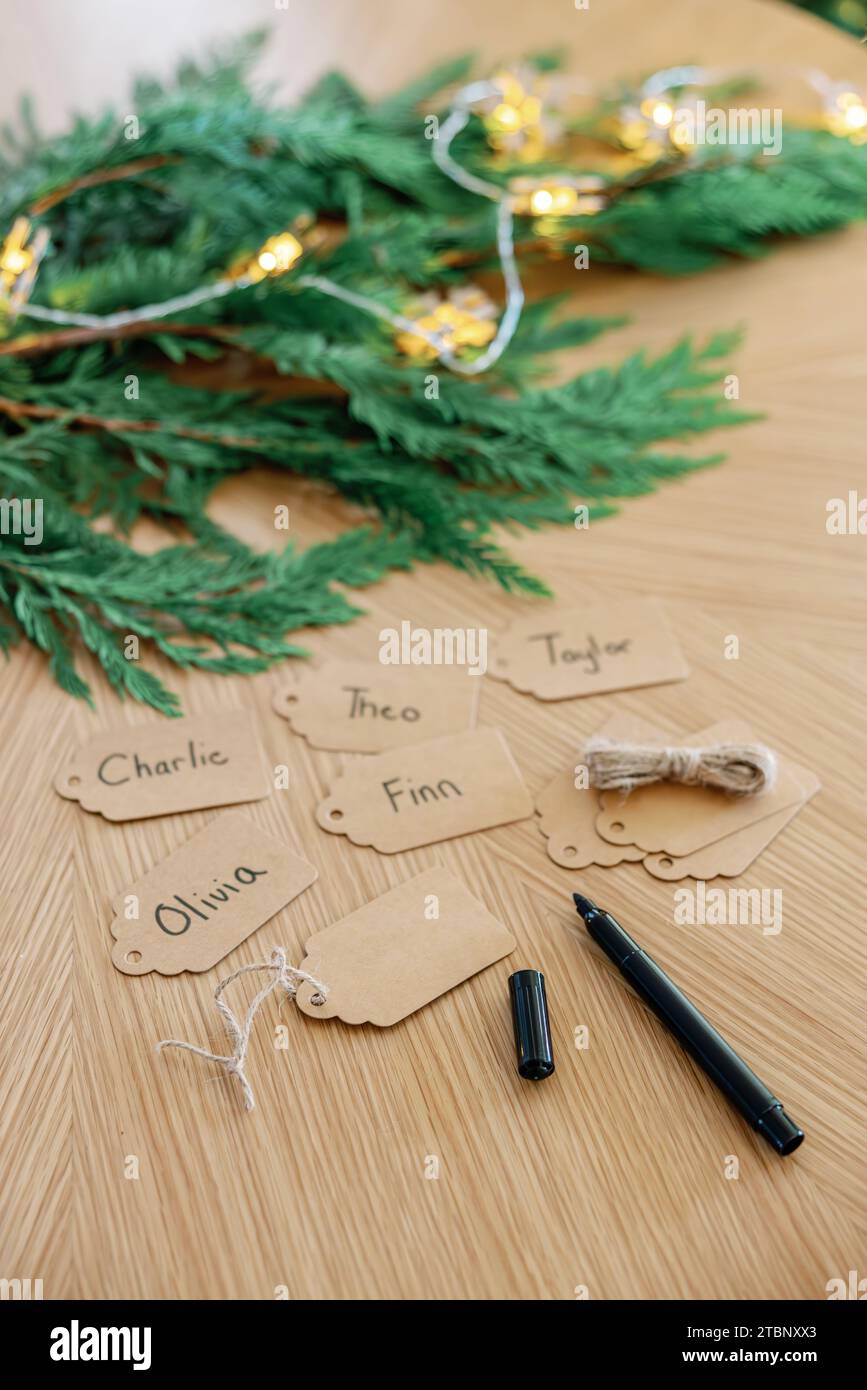 Etichette regalo scritte a mano per le feste con vegetazione natalizia su superficie in legno Foto Stock