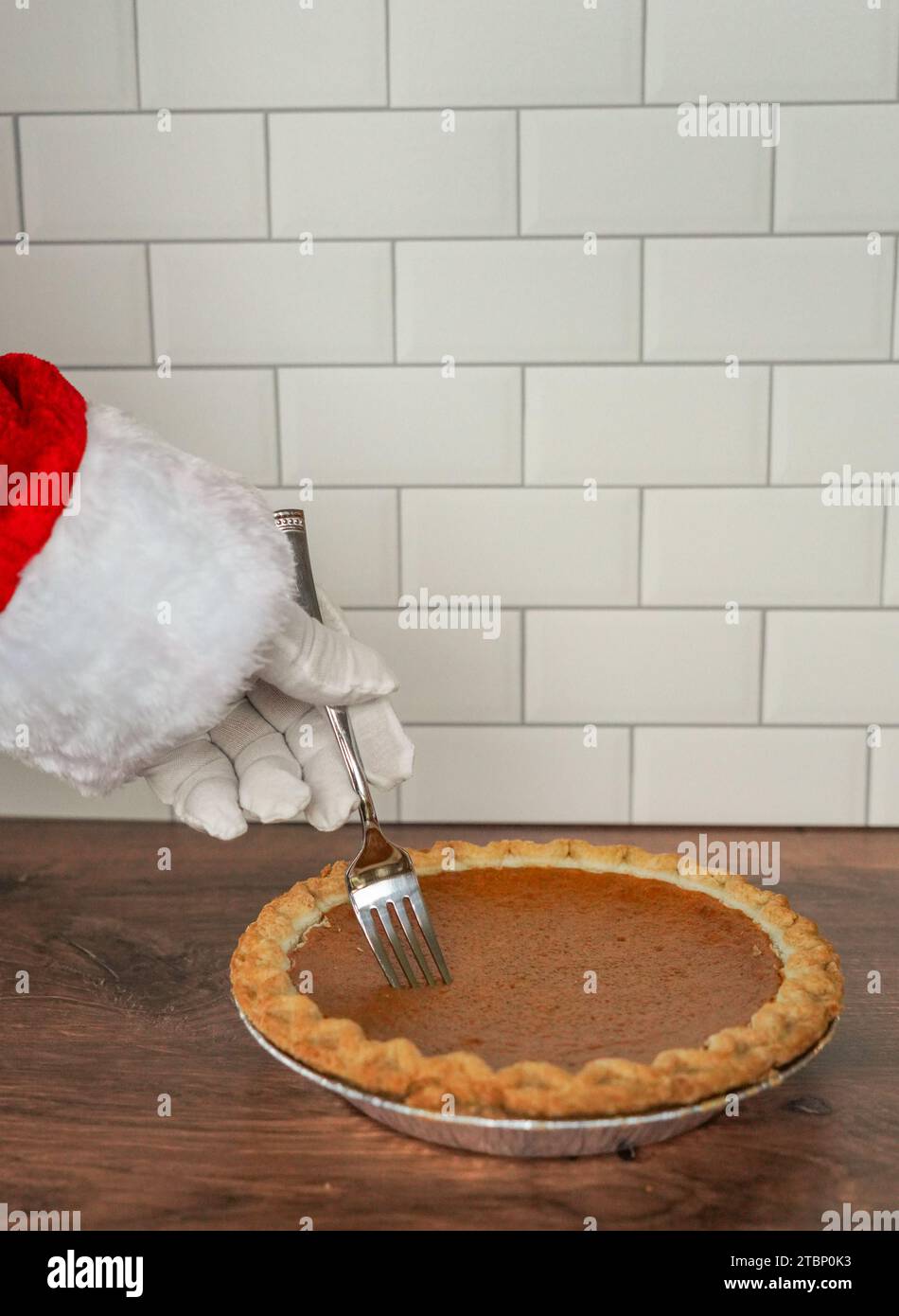 Babbo Natale con una forchetta e una torta di zucca in cucina Foto Stock