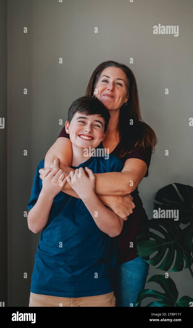 Madre e figlio felici che si abbracciano giocosi a casa. Foto Stock