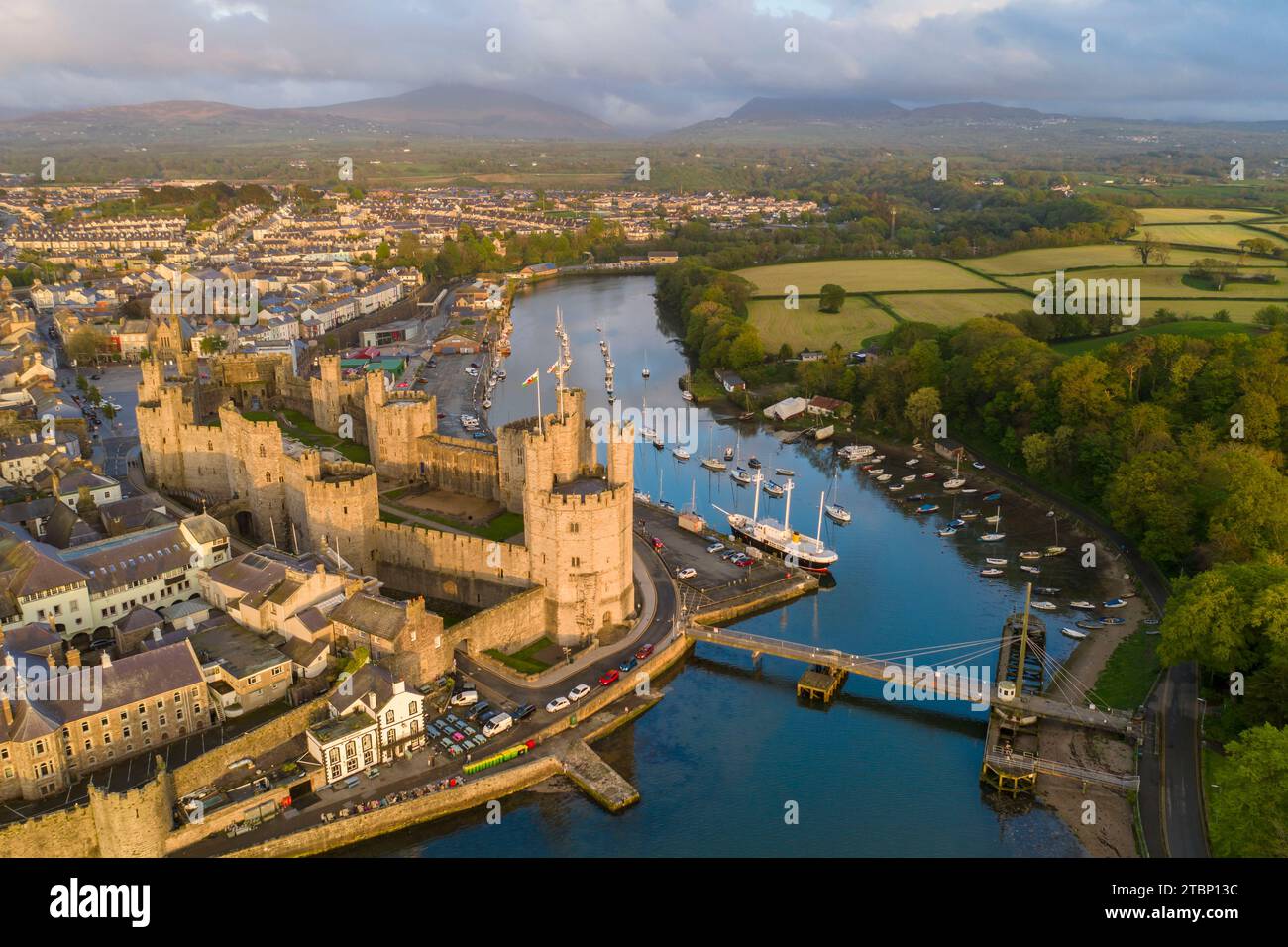 Vista aerea del castello di Caernarfon e della città alla splendida luce del sole serale, Caernarfon, Galles, Regno Unito. Primavera (maggio) 2023. Foto Stock