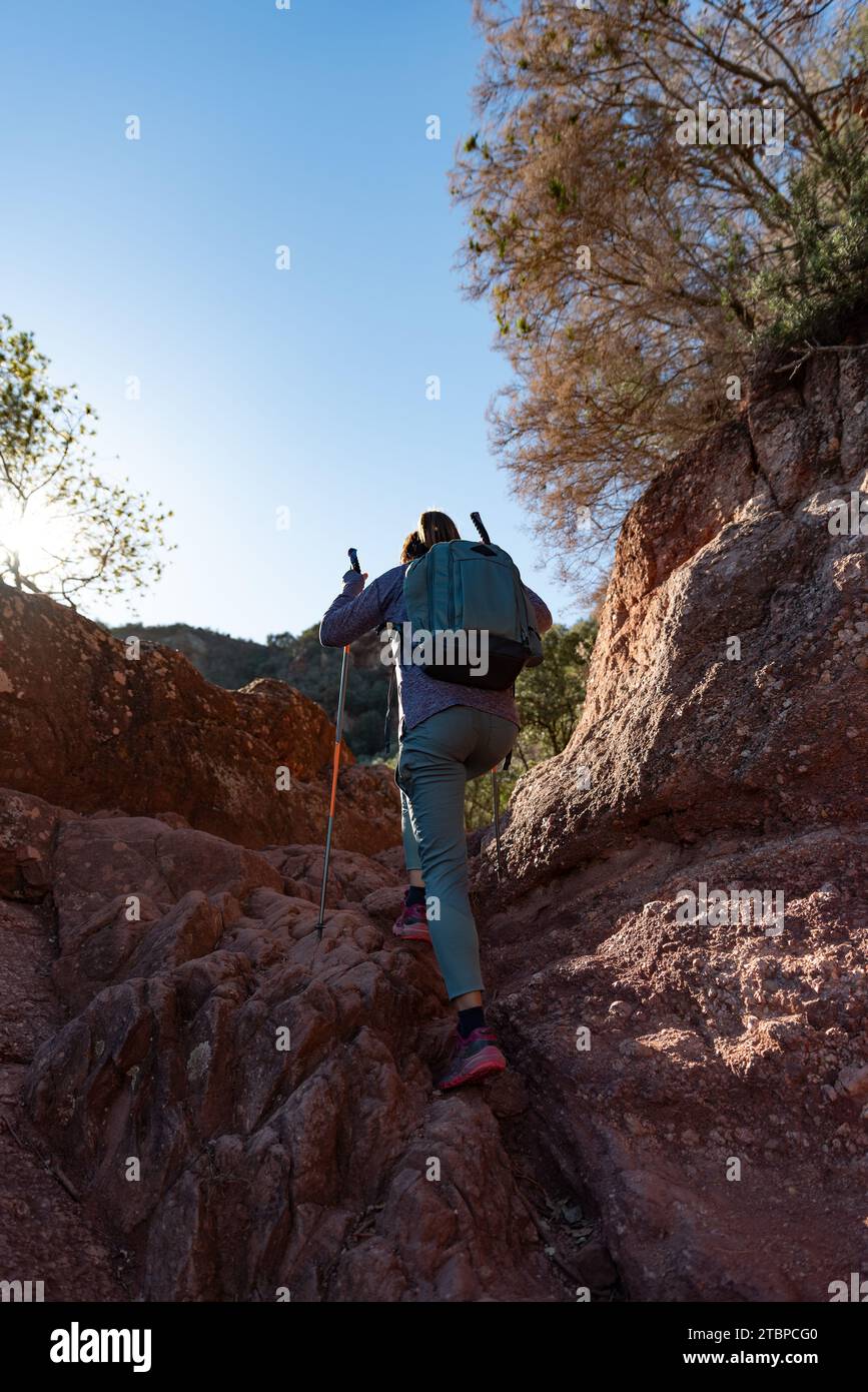 La donna sale la montagna nel Parco naturale Garraf, sostenuta da bastoni da trekking. Foto Stock