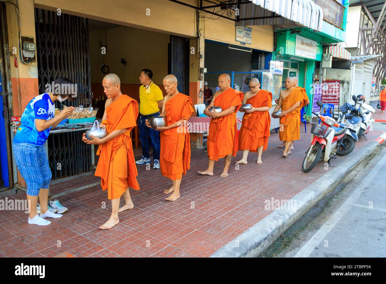 Lampang, Thailandia - 2 dicembre 2023: Monaci buddisti thailandesi Theravada che camminano per le elemosine mattutine a Nakhon Lampang, Thailandia. Foto Stock