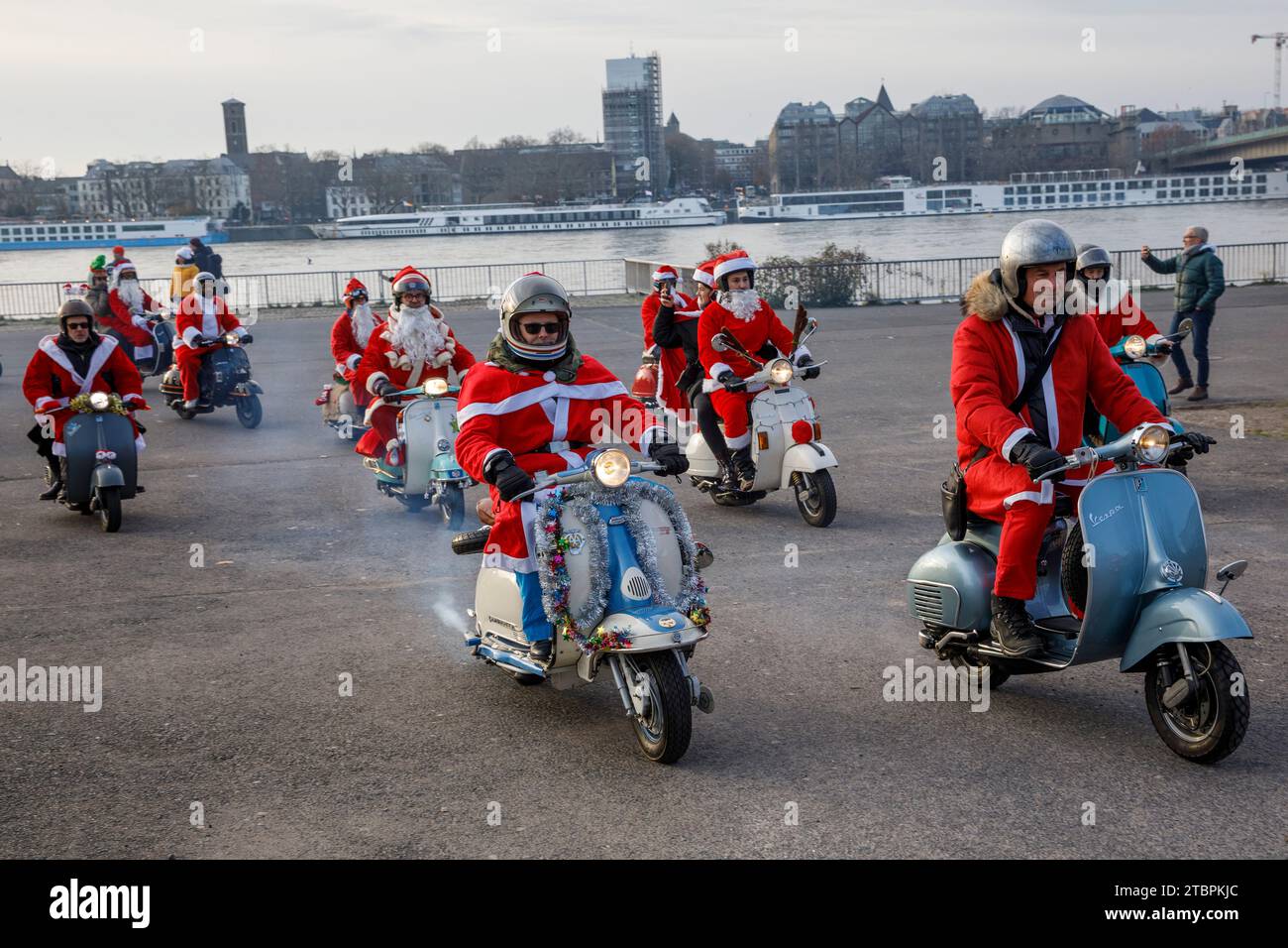 I membri del club di scooter Vespa RheinSchalter Koeln vestiti come Santas si riuniscono sul Deutzer Werft prima di un giro attraverso la città, Colonia, Germania. La Foto Stock