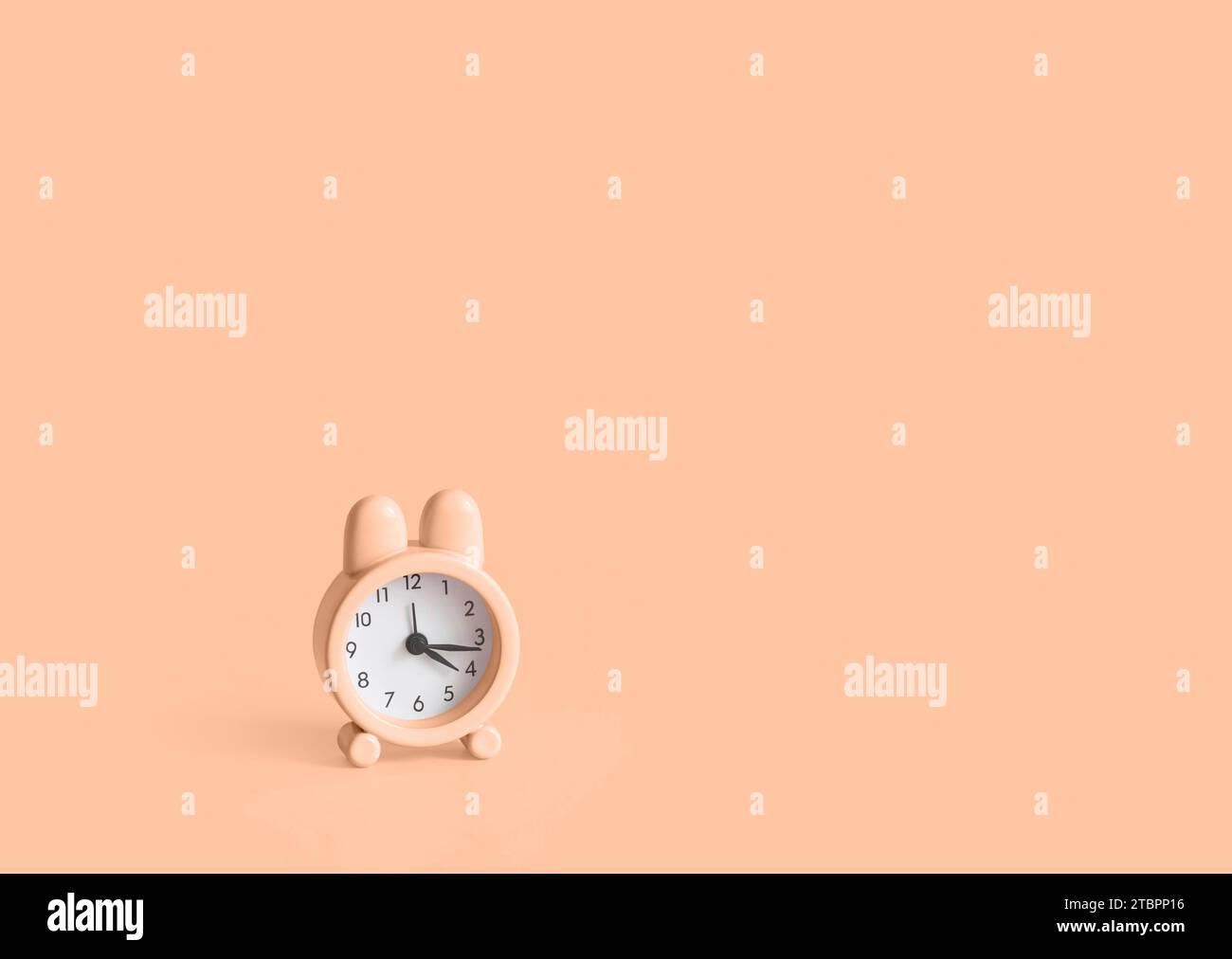 Piccola sveglia Peach Fuzz Bunny di sfondo. Colore trendy dell'anno 2024 Peach Fuzz. Pasqua. Copia spazio. Foto Stock