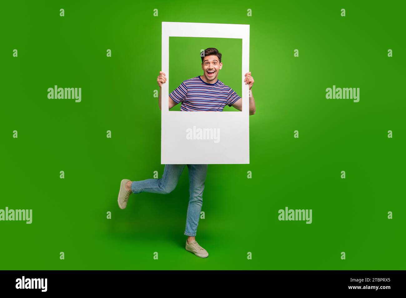 Foto a grandezza naturale di pantaloni in denim vestiti da ragazzo estatici e felicissimi sorridenti in una cornice isolata su sfondo verde Foto Stock