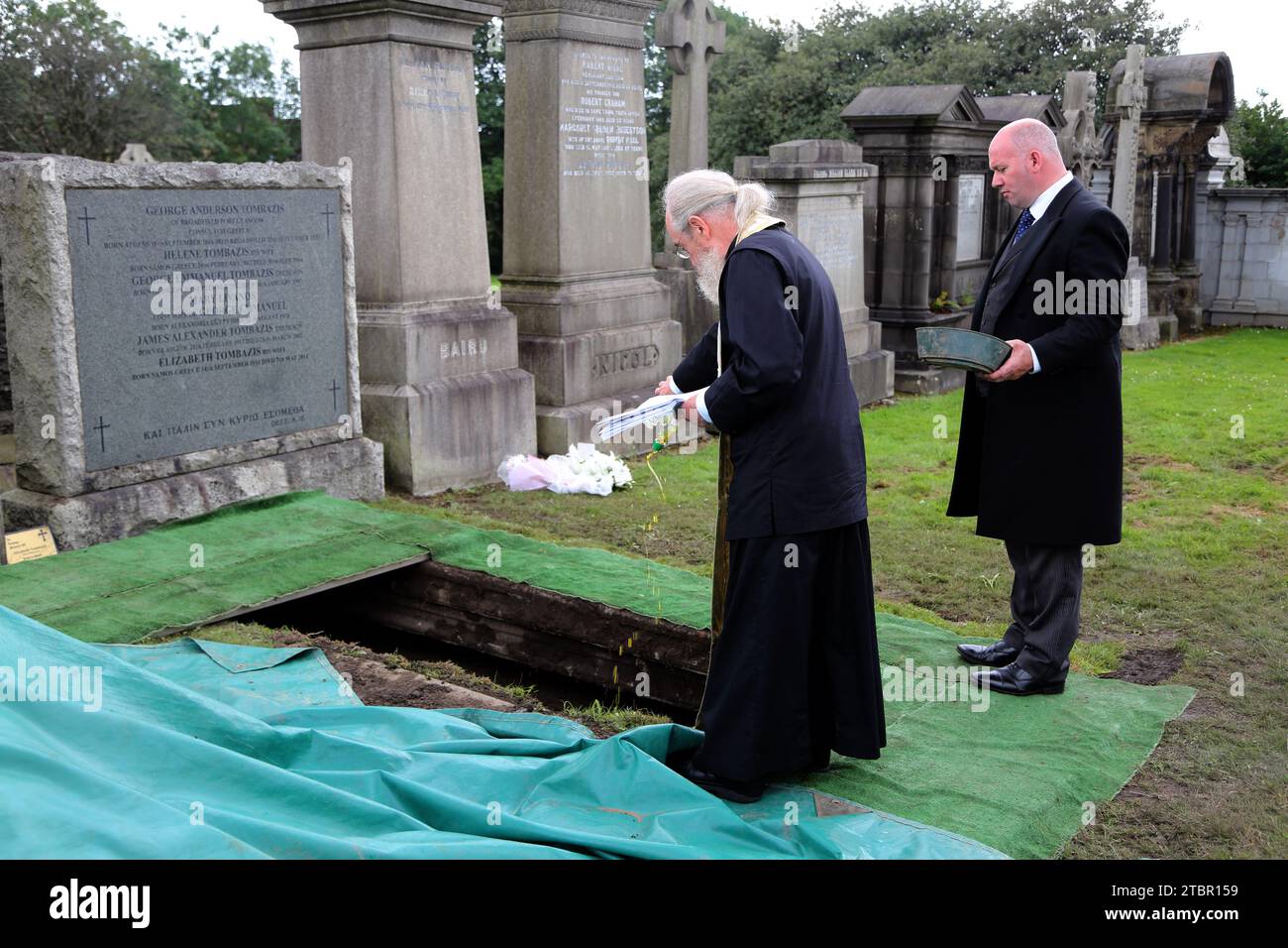 Funerale greco-ortodosso di Glasgow in Scozia alla necropoli di Glasgow - prete che versa olio d'oliva sul Coffin al committal Service Foto Stock