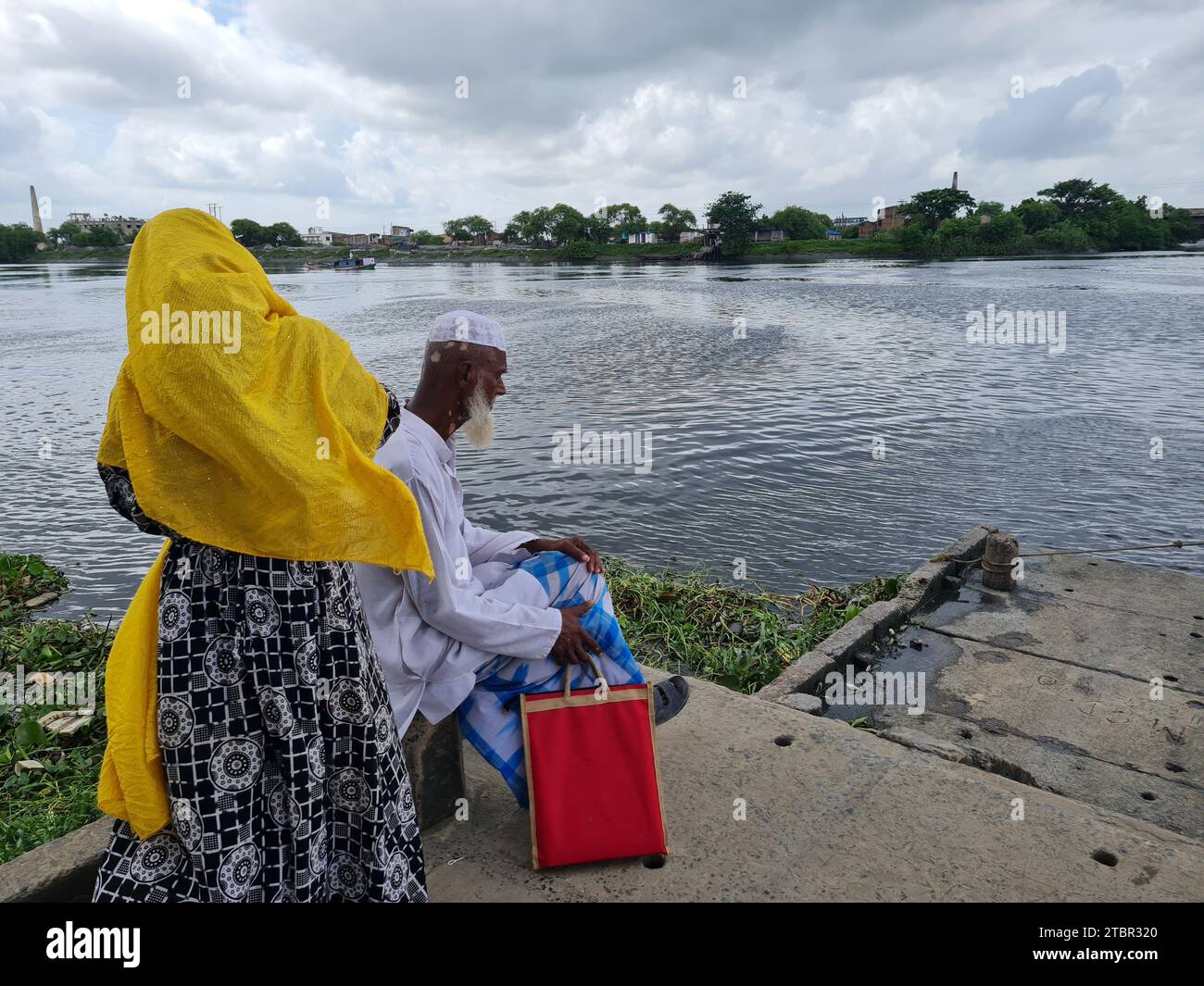 Gli abitanti dei villaggi rurali dell'India aspettano un'imbarcazione da trasporto locale nella zona lungo il fiume. Foto Stock