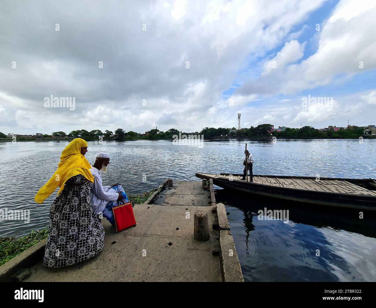 Gli abitanti dei villaggi rurali dell'India aspettano un'imbarcazione da trasporto locale nella zona lungo il fiume. Foto Stock