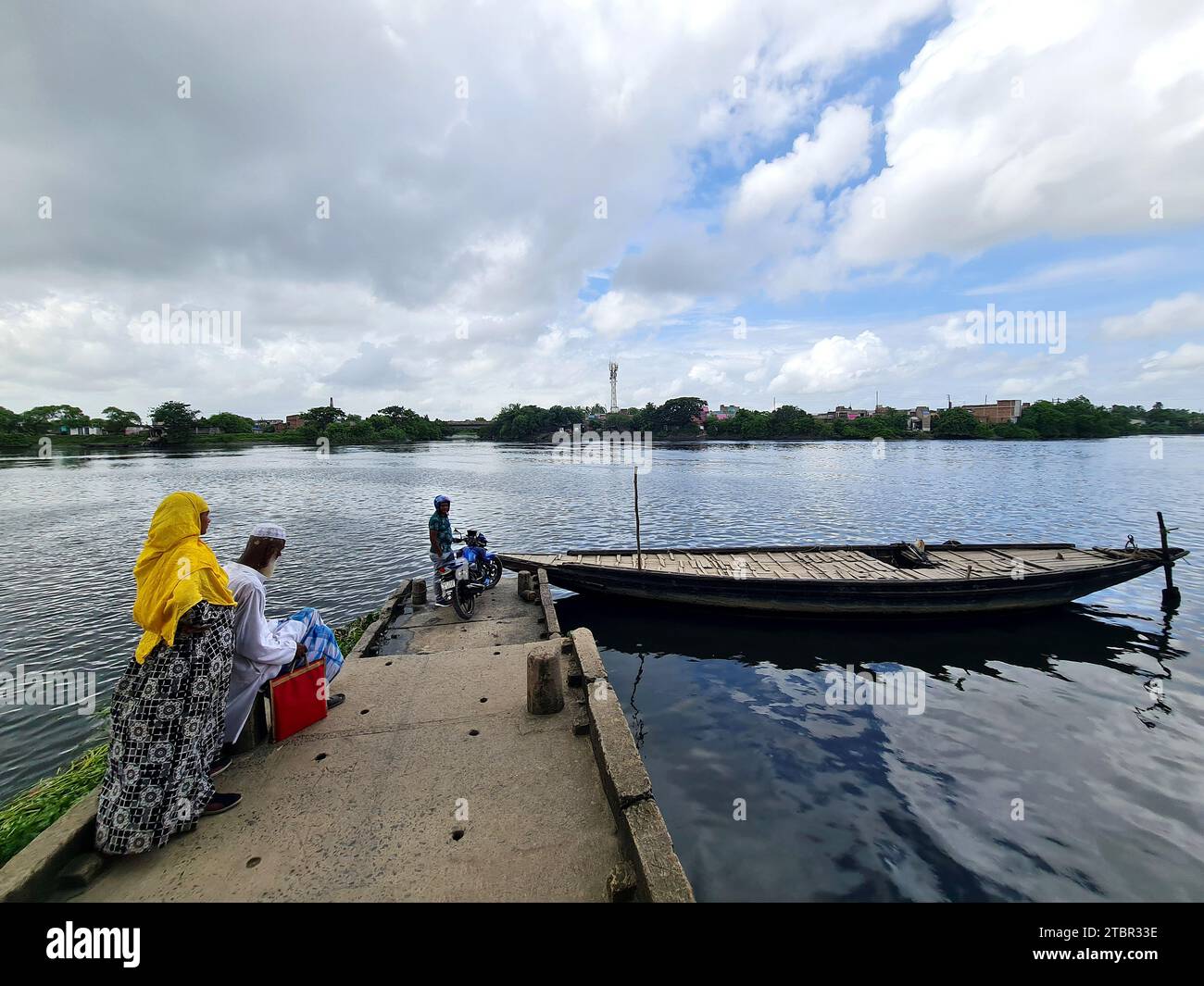 Gli abitanti dei villaggi rurali dell'India aspettano un'imbarcazione da trasporto locale nella zona lungo il fiume. Foto Stock