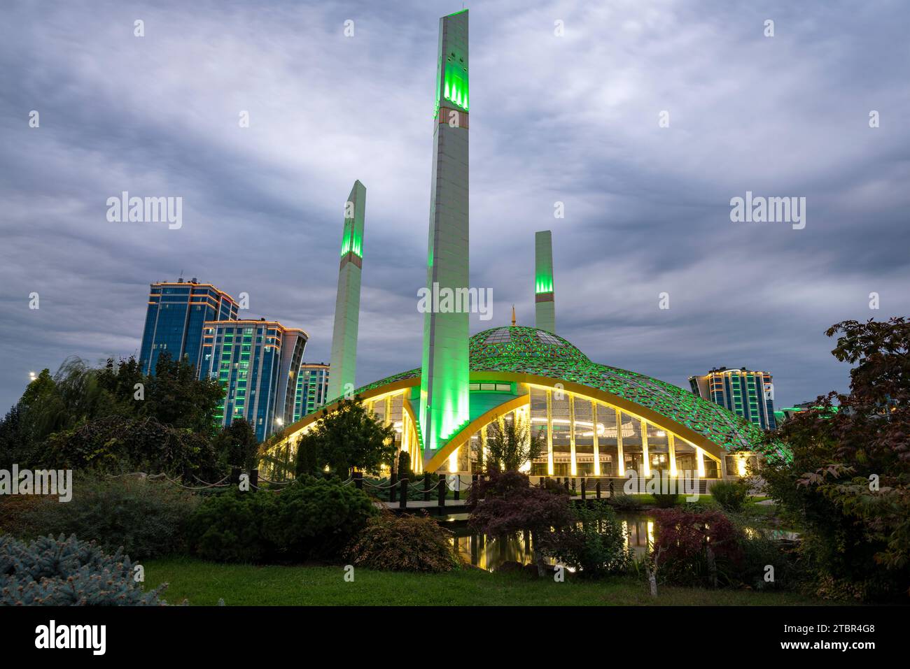 ARGUN, RUSSIA - 28 SETTEMBRE 2021: Moschea "cuore della madre" illuminata da una notte verde su un crepuscolo nuvoloso di settembre Foto Stock