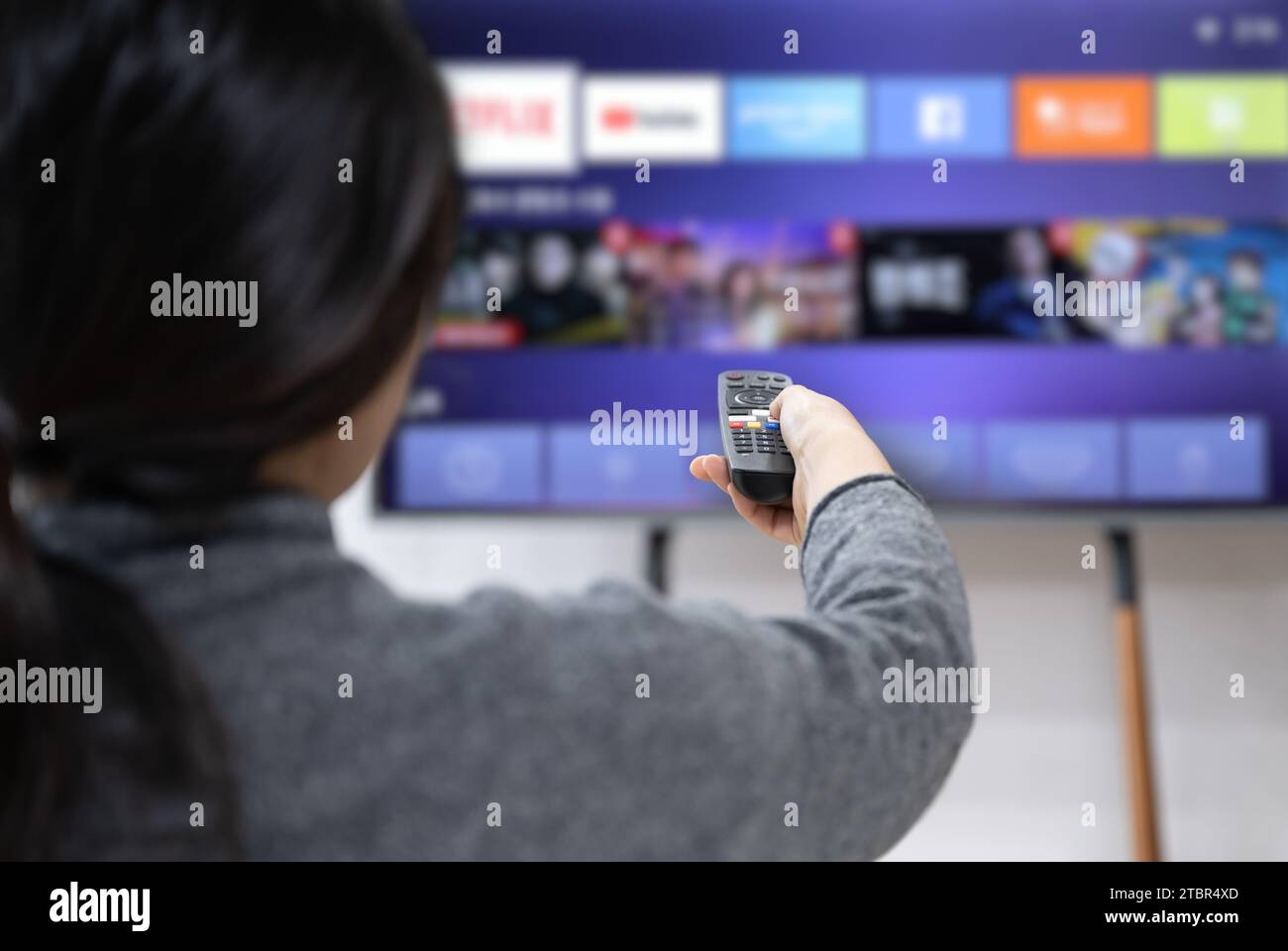 Una donna sperimenta il servizio OTT utilizzando uno smart TV a casa Foto Stock