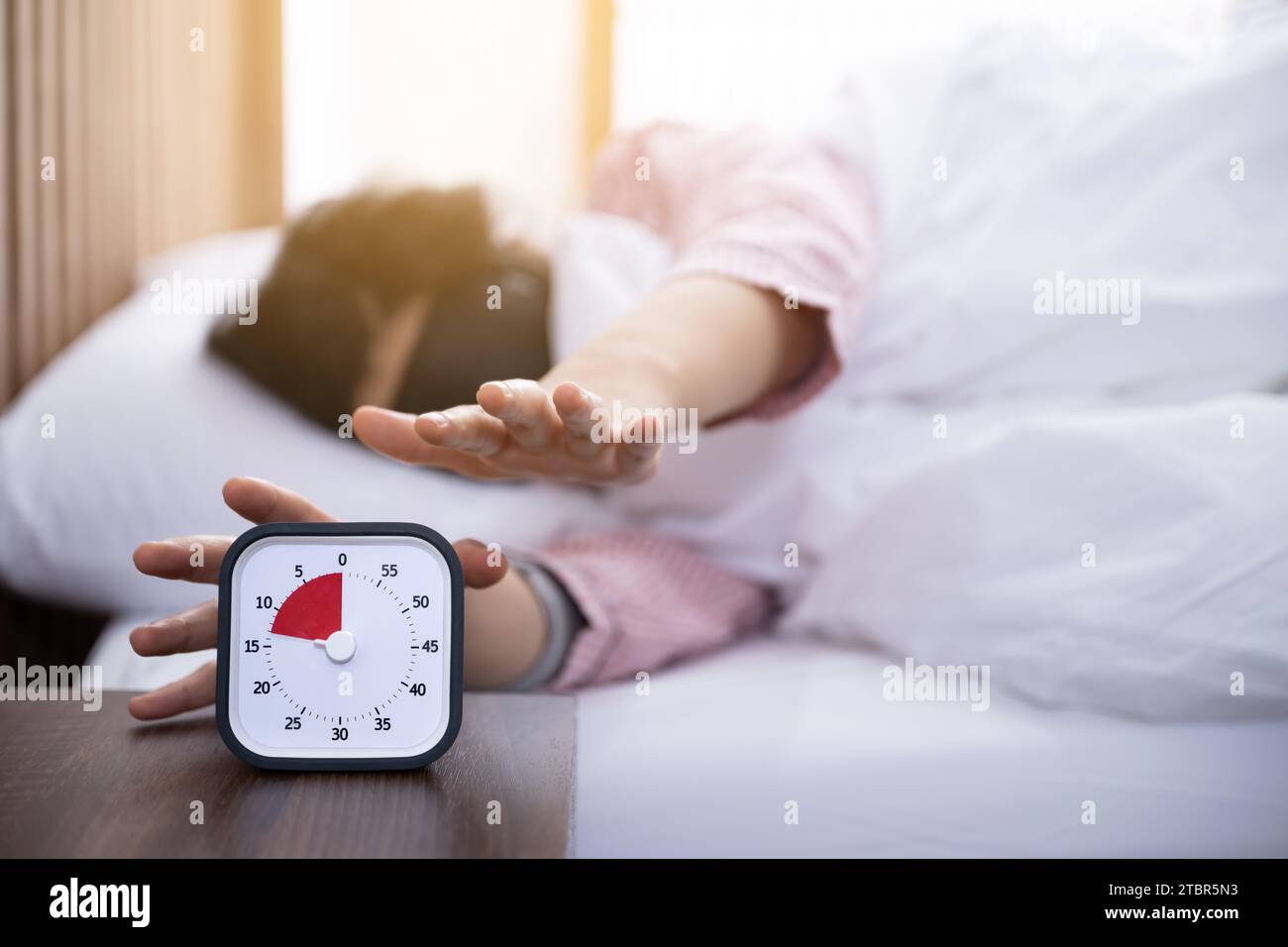 Una donna che indossa un oculare cerca di toccare il timer mentre si sveglia Foto Stock