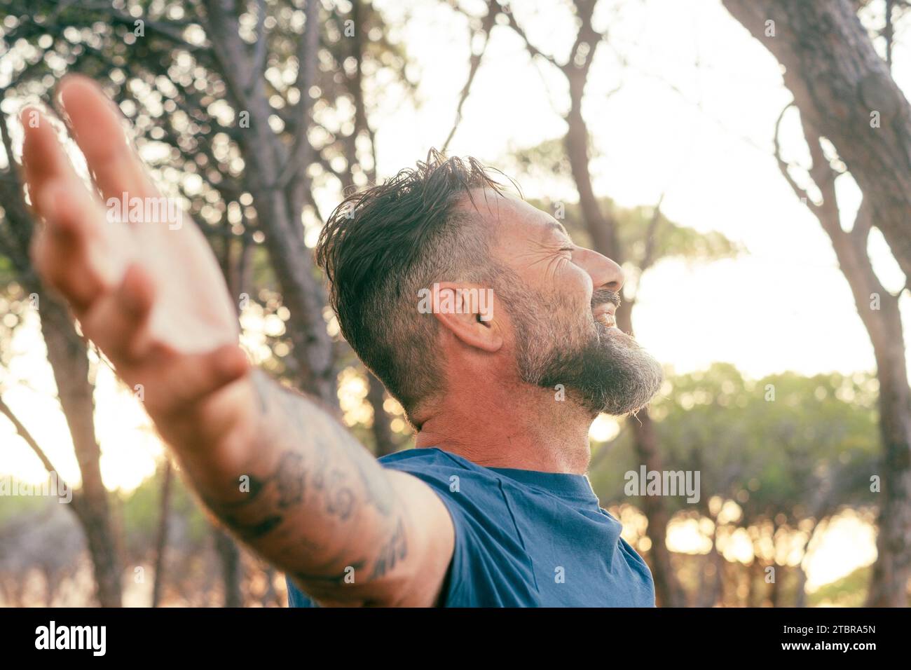 Primo piano del ritratto laterale dell'uomo che si allunga alle braccia sorridendo e godendosi la luce del tramonto in attività ricreative all'aperto nella natura. Felice espressione serena adulti adulti adulti adulti adulti adulti adulti adulti adulti adulti che si godono all'esterno Foto Stock