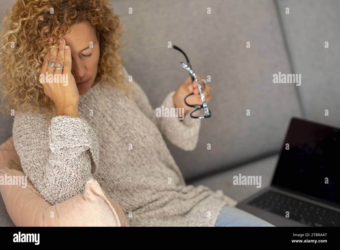 Depressa frustrata giovane donna adulta che soffre di mal di testa, emicrania, volto toccante, testa con occhi chiusi, sensazione di stress, malato, stanco, pensare alle cattive notizie, problemi, crisi Foto Stock