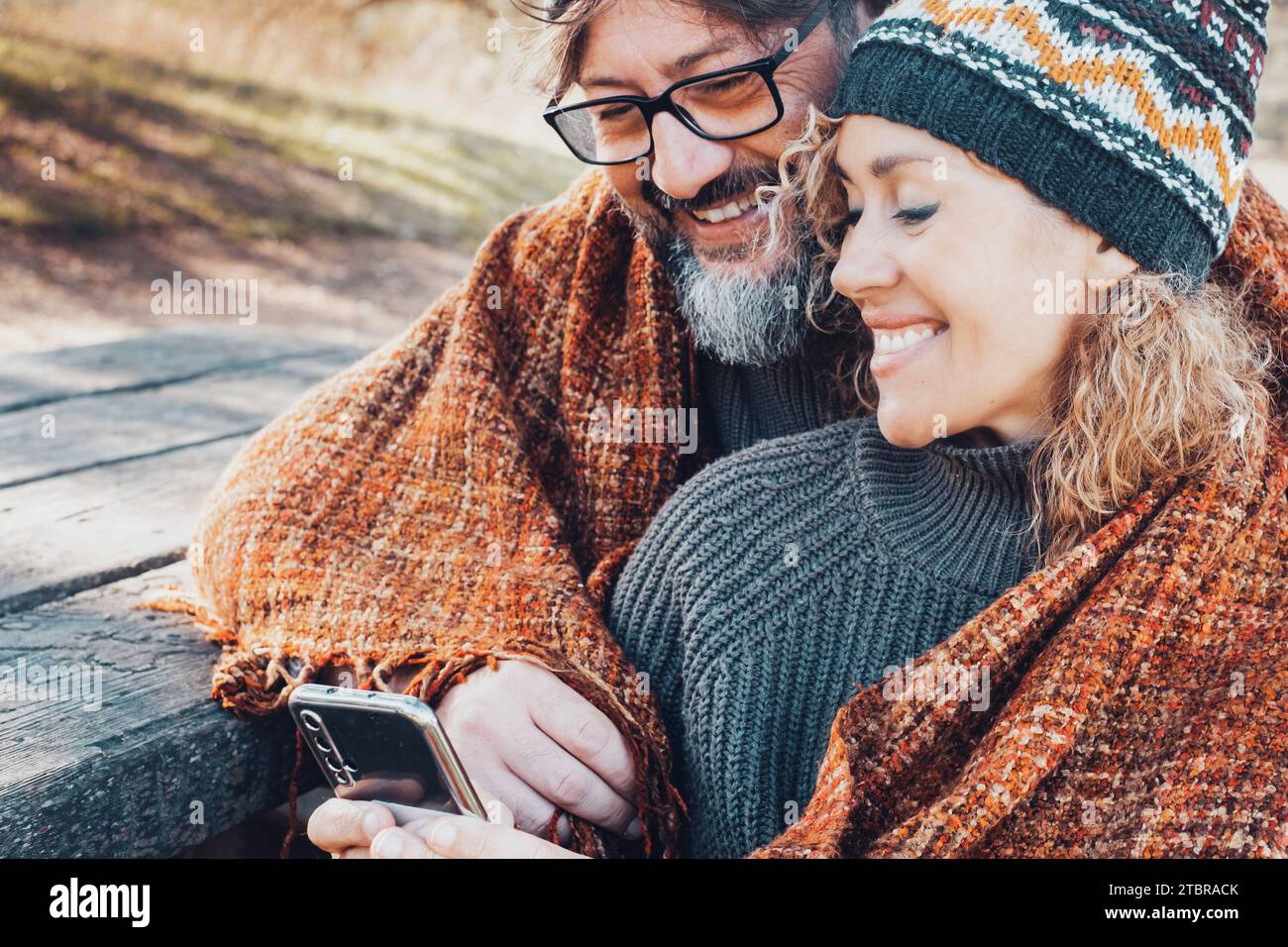 Coppia felice che utilizza il telefono insieme per attività ricreative all'aperto e una giornata romantica al parco. Tecnologia cellulare per la condivisione dell'amore e delle relazioni. Uomo e donna che chiacchierano e messaggavano all'aperto Foto Stock