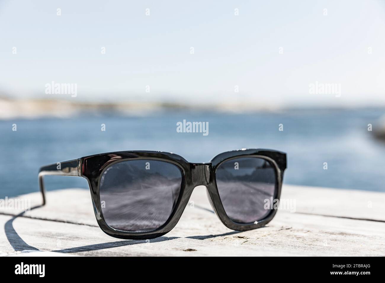 Occhiali da sole su un ponte in legno sulla spiaggia Foto Stock